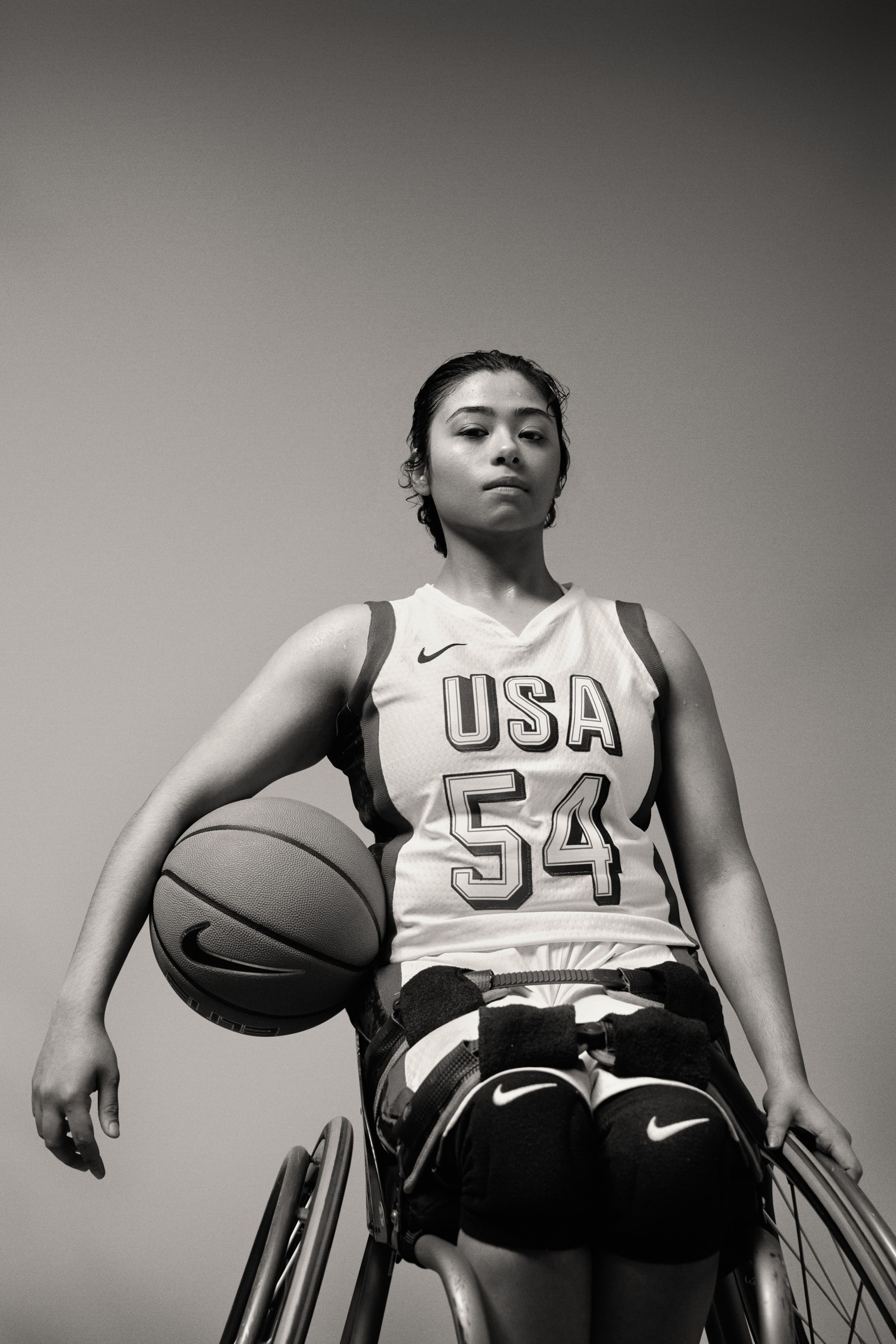 Black and white photo of Ixhelt Gonzalez holding a basketball under her arm.