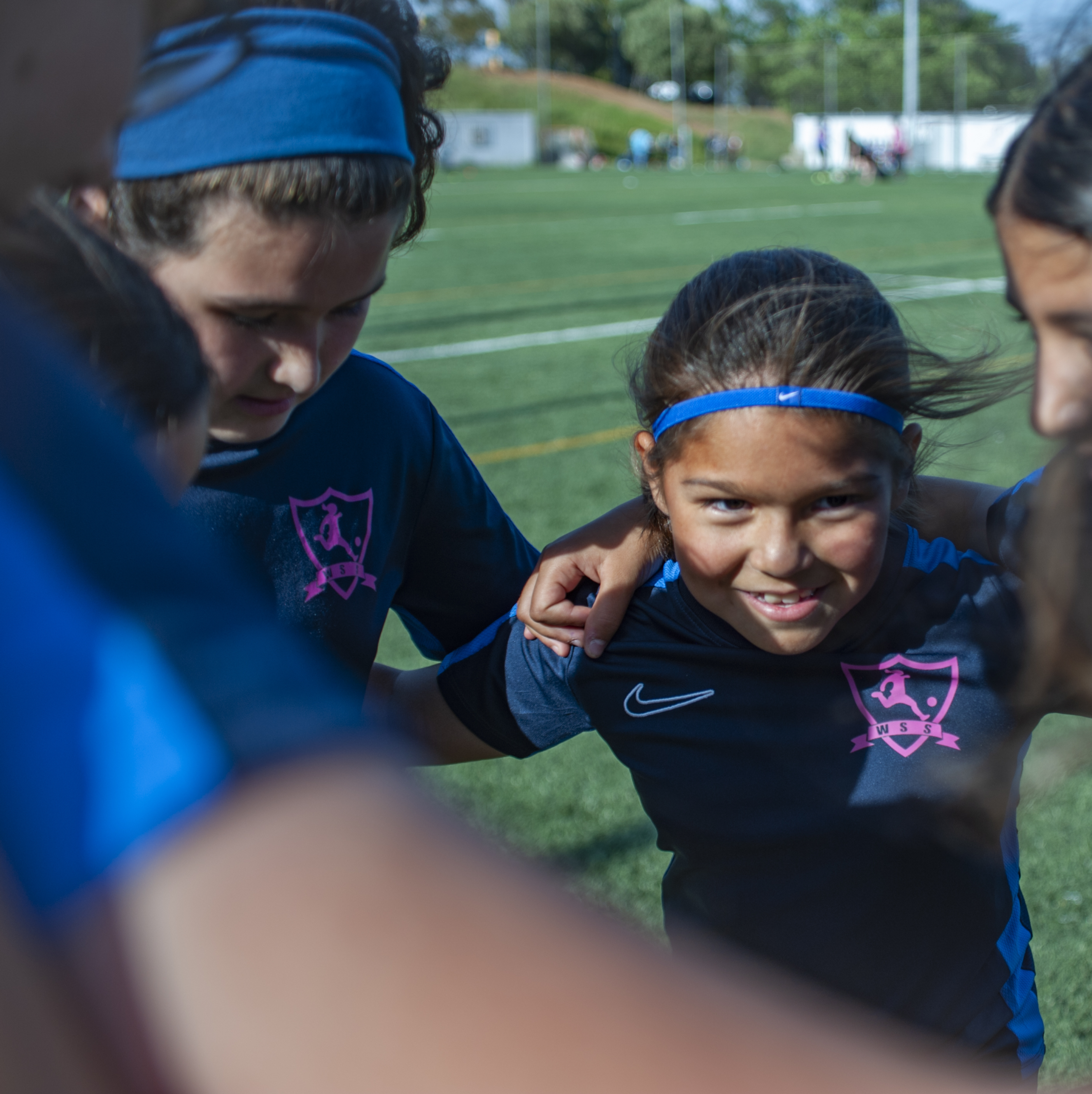 A young girl huddles with her teammates on a football pitch in Barcelona.