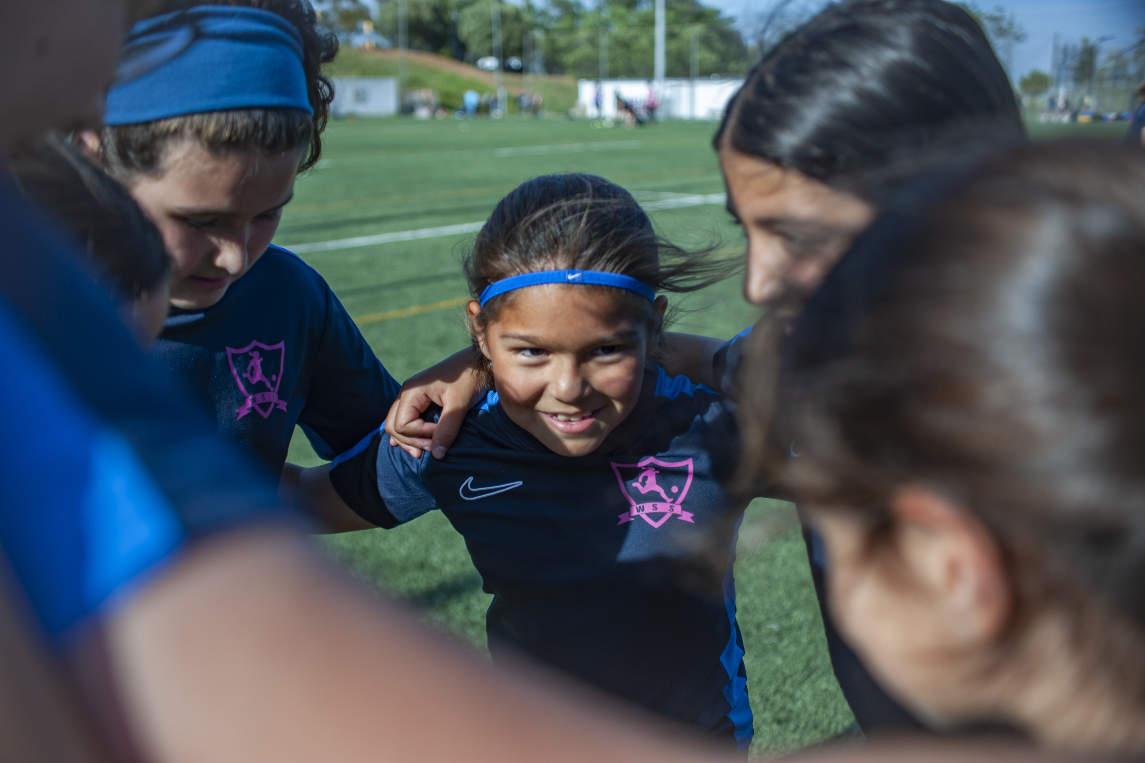 A young girl huddles with her teammates on a football pitch in Barcelona.