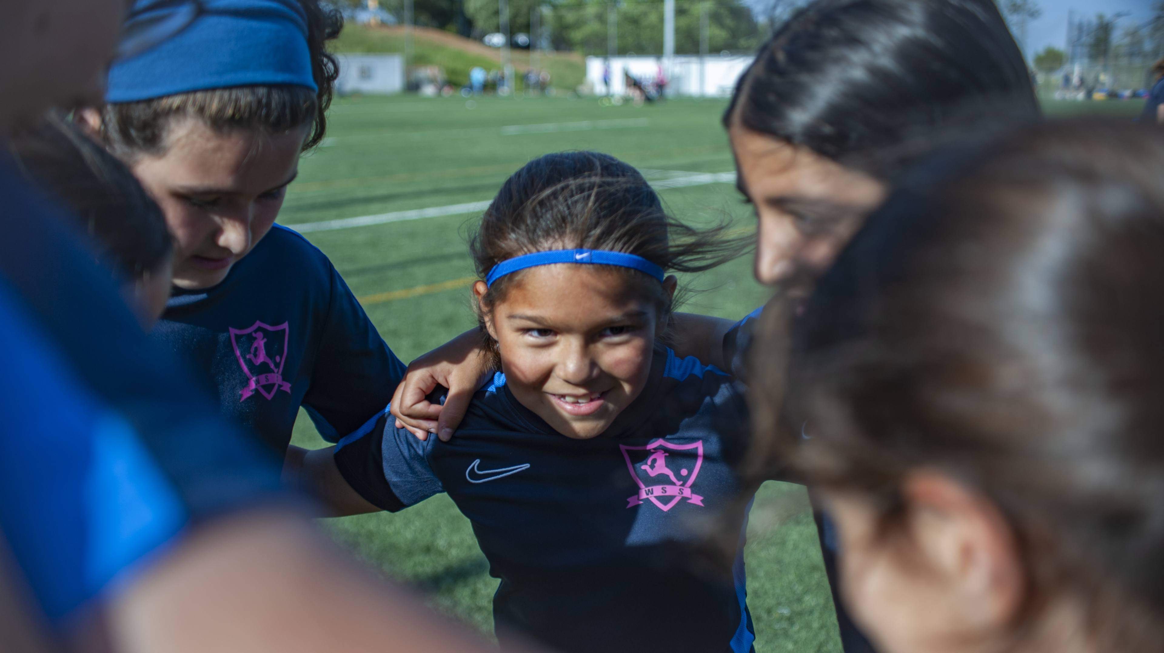 A young girl huddles with her teammates on a football pitch in Barcelona.