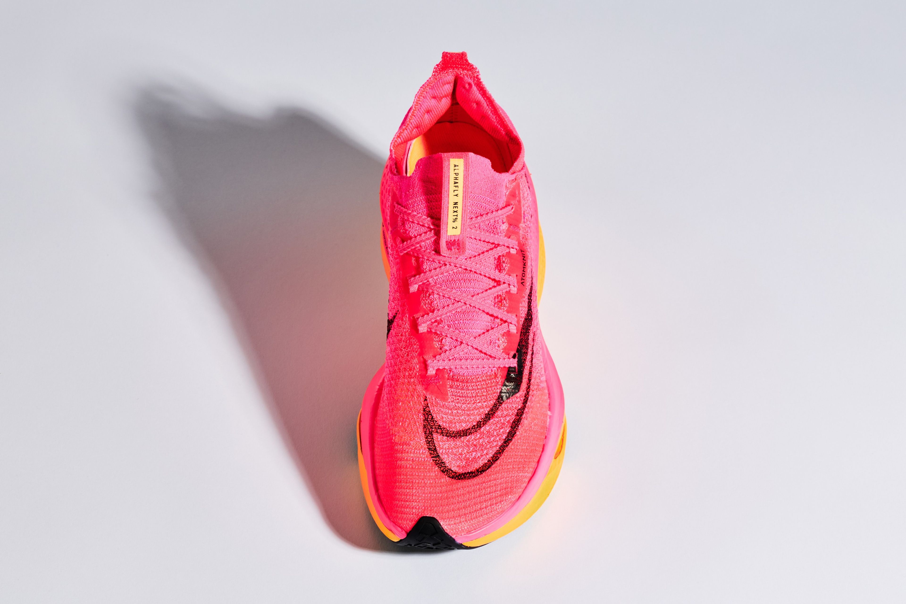 Nike AlphaFly Next% 2 running shoe in Atomic Pink Flyknit upper with yellow midsole and black Nike Swoosh, top-down studio view