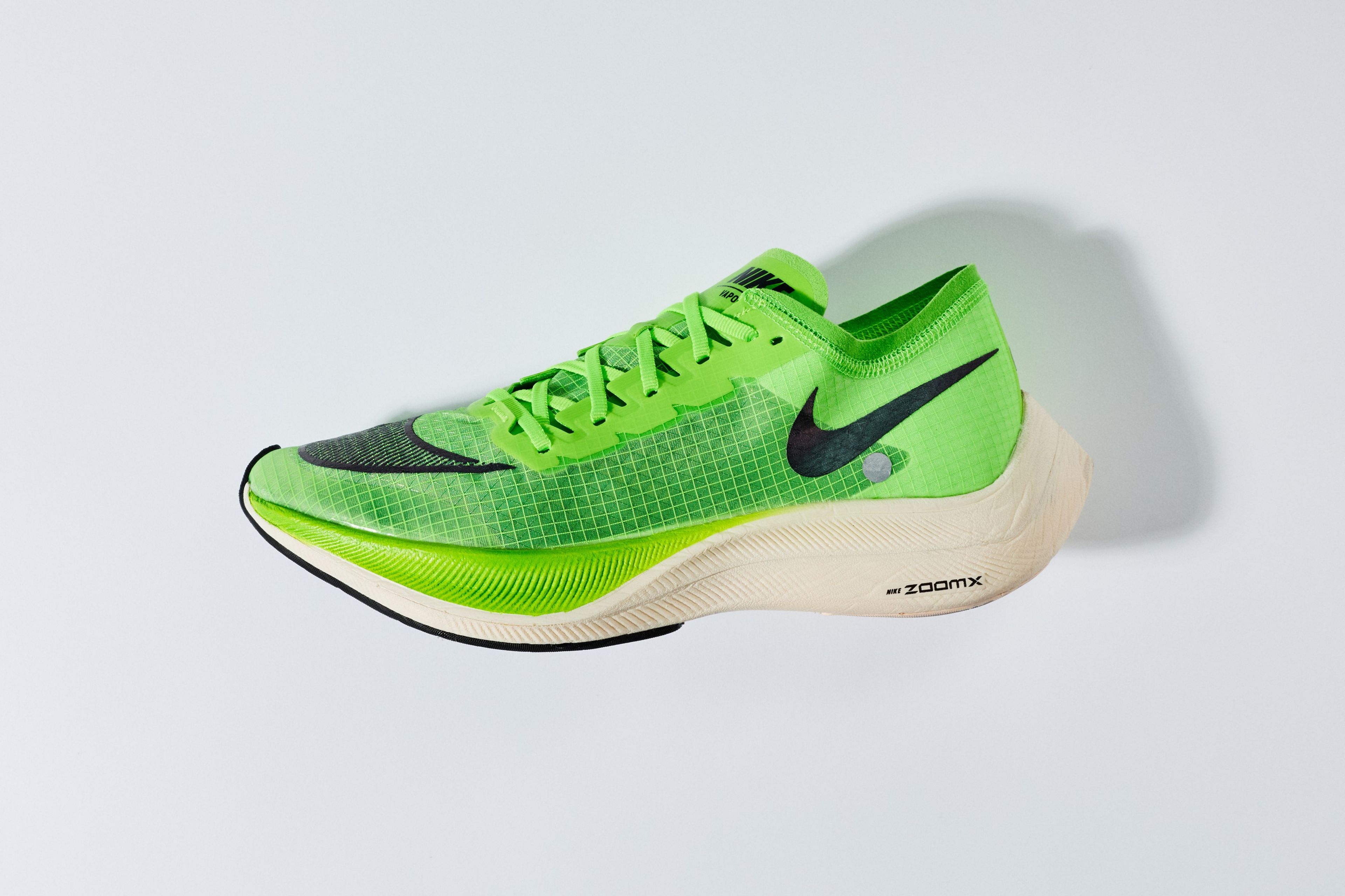 Nike ZoomX Vaporfly NEXT% running shoe in electric green with black Swoosh, white ZoomX foam midsole, and mesh upper on a light gray background.