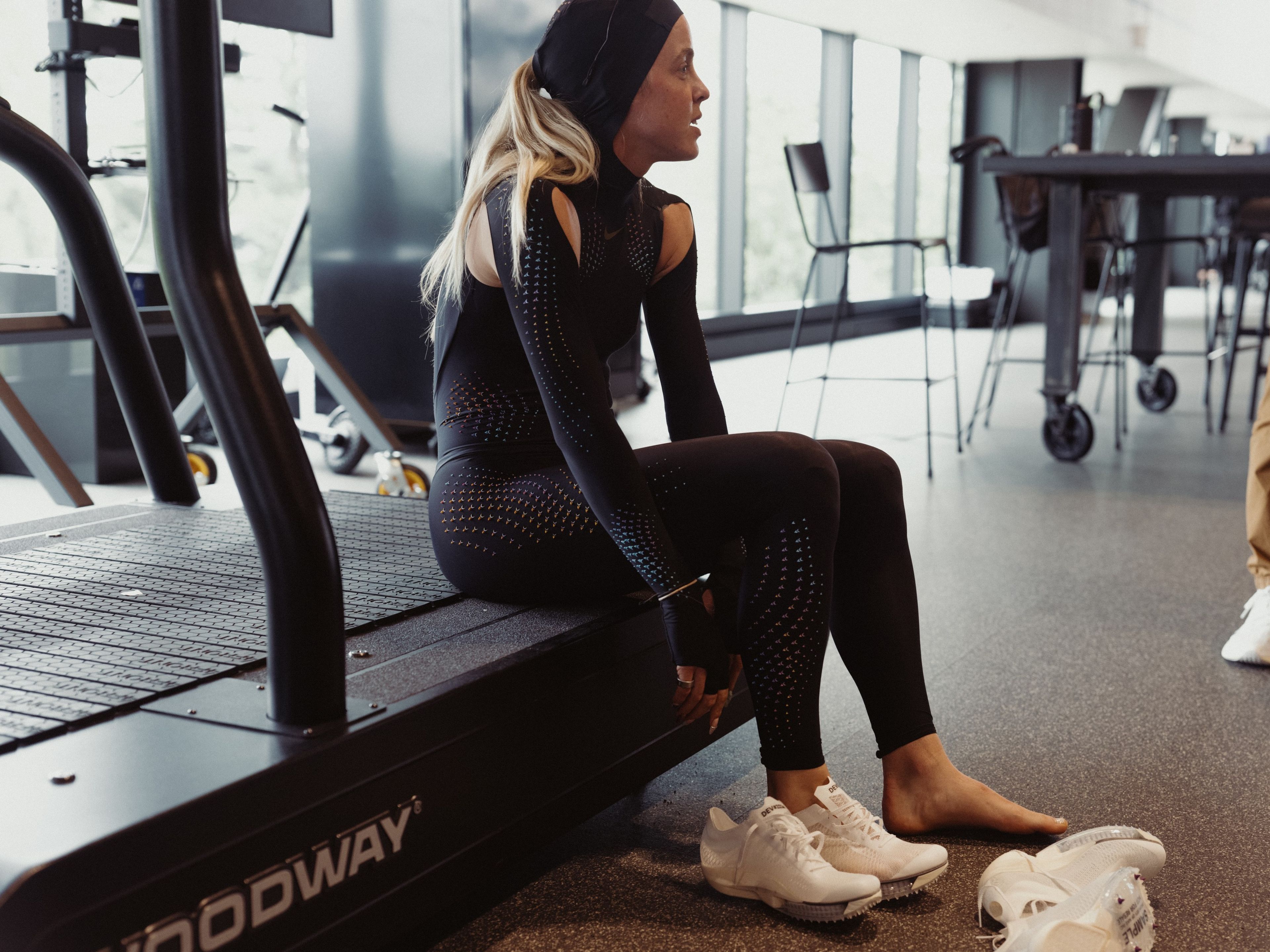 Keely Hodgkinson tries on a pair of track spikes while wearing a black full-body speed suit.