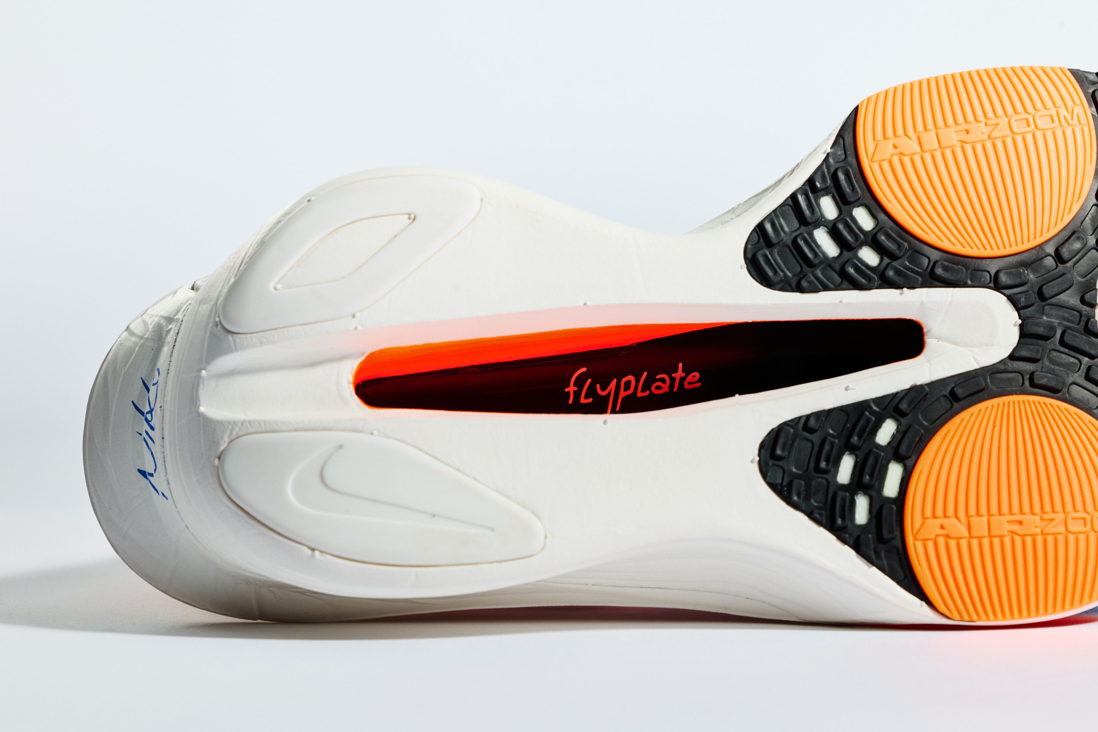 Close-up of Nike Alphafly 3 running shoe outsole showing Flyplate cutout with orange plate, Air Zoom rubber pods, black traction pattern, and white midsole.