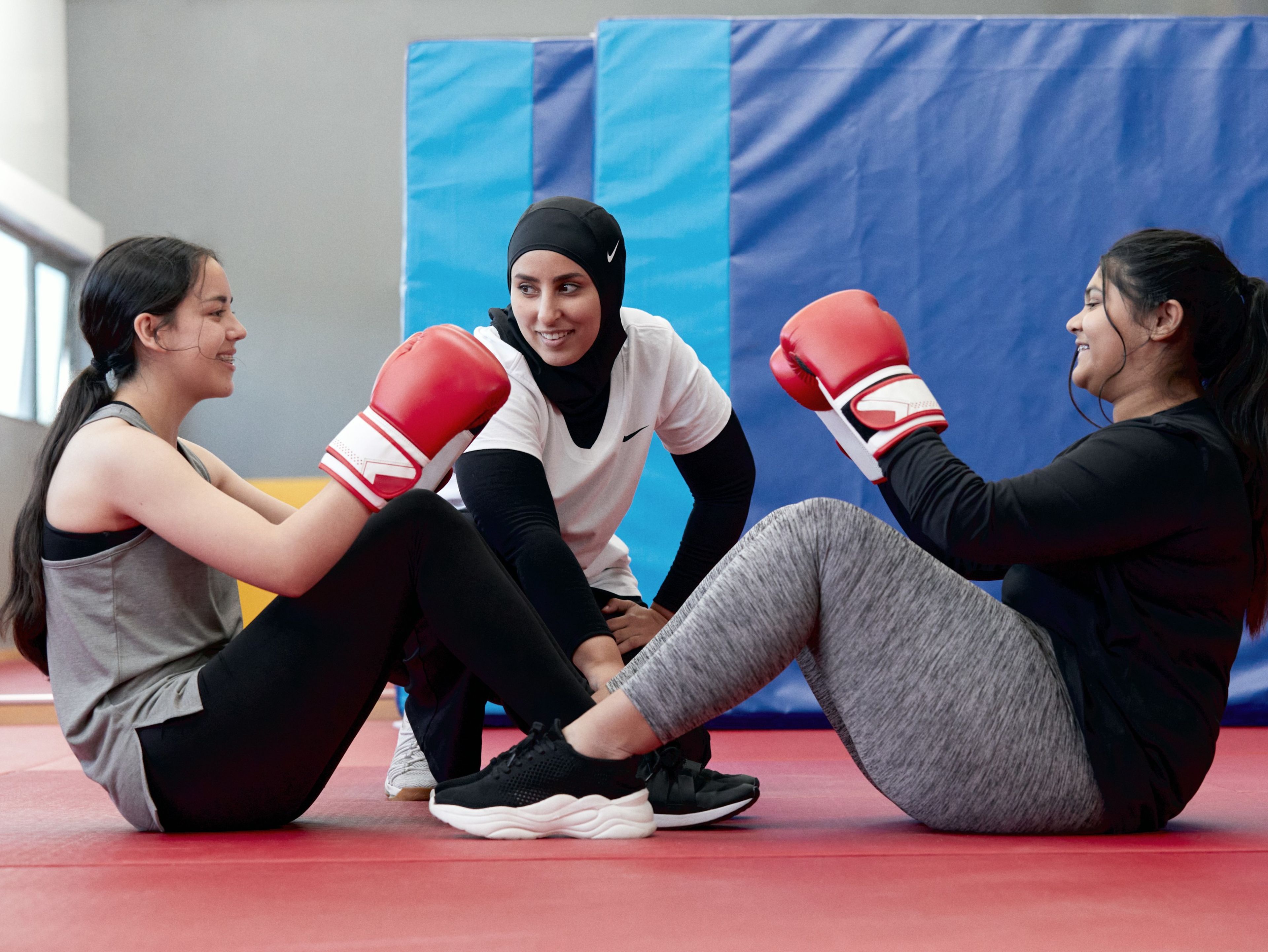 Two girls participate in a boxing exercise with a Nike coach.
