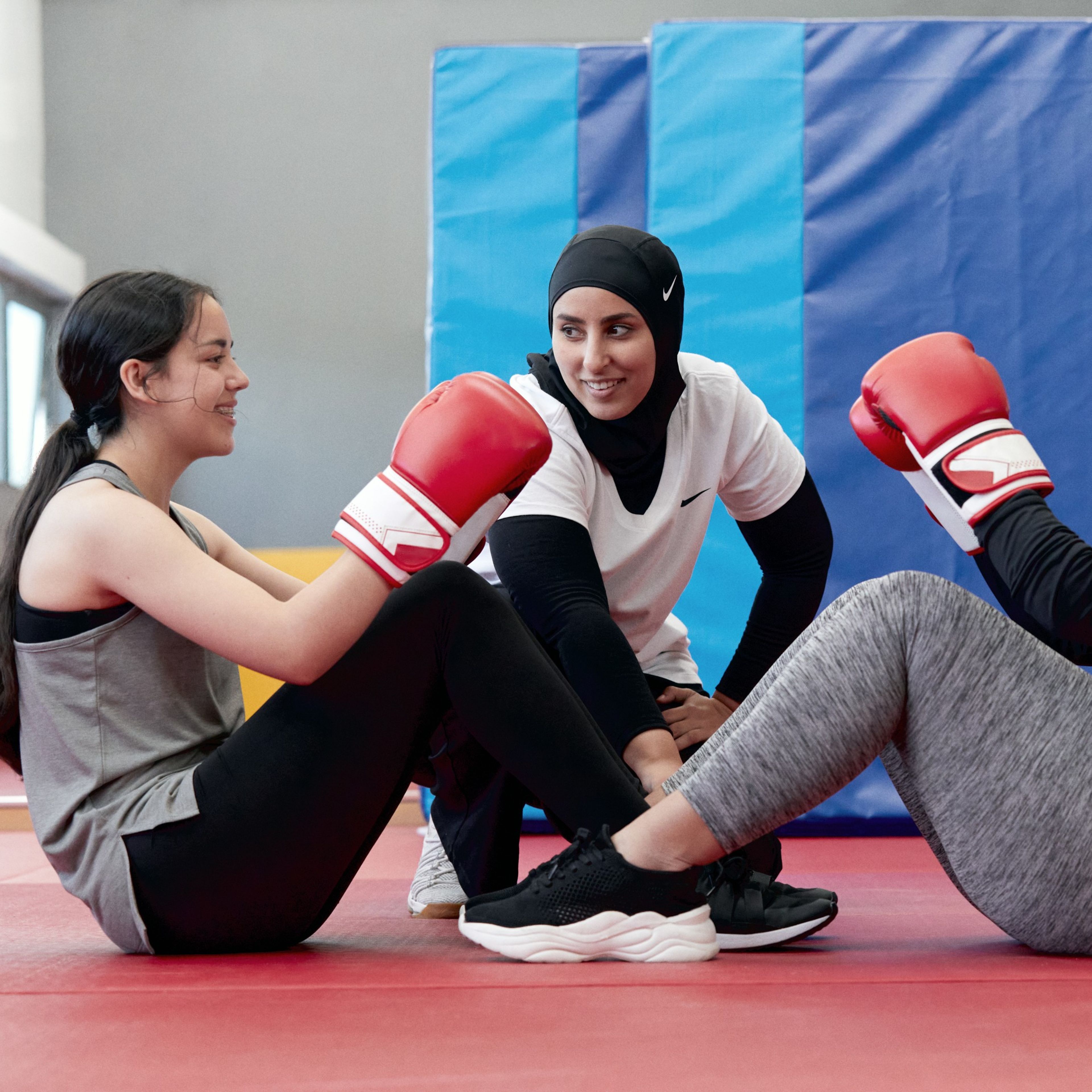 Two girls participate in a boxing exercise with a Nike coach.