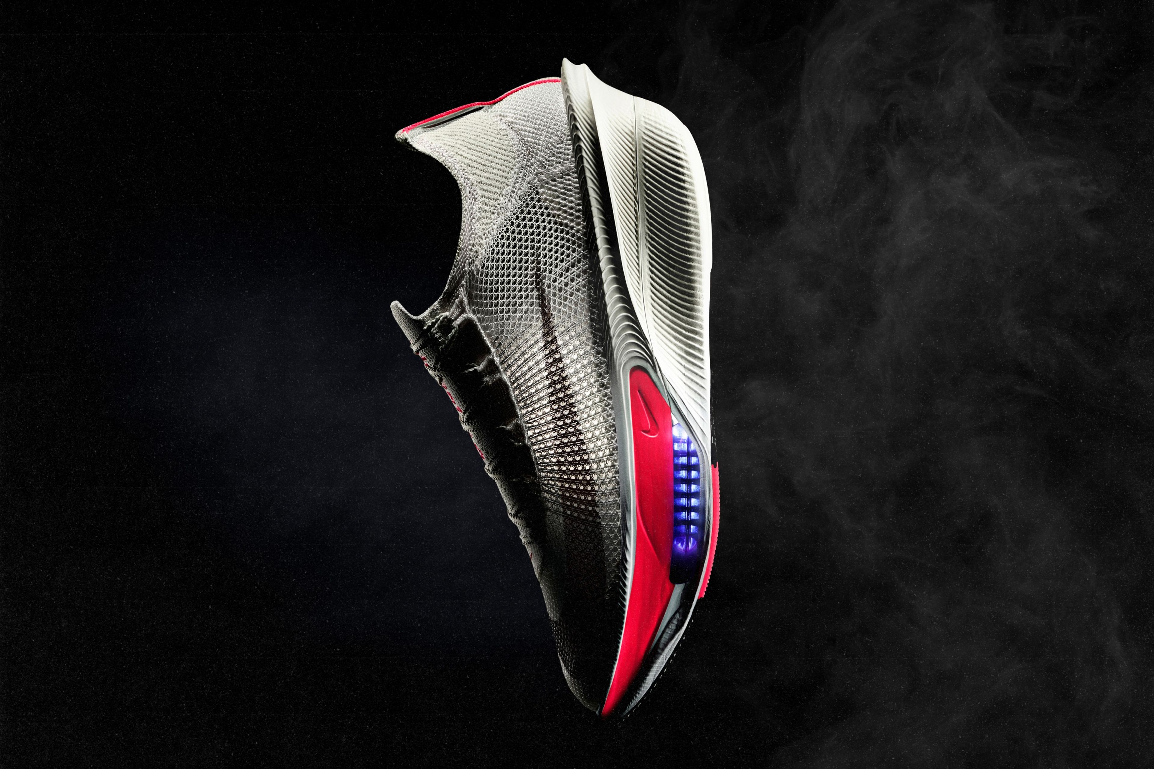 Nike Alphafly 4 racing shoe in gray and red floating against a black background, showing visible Air Zoom units