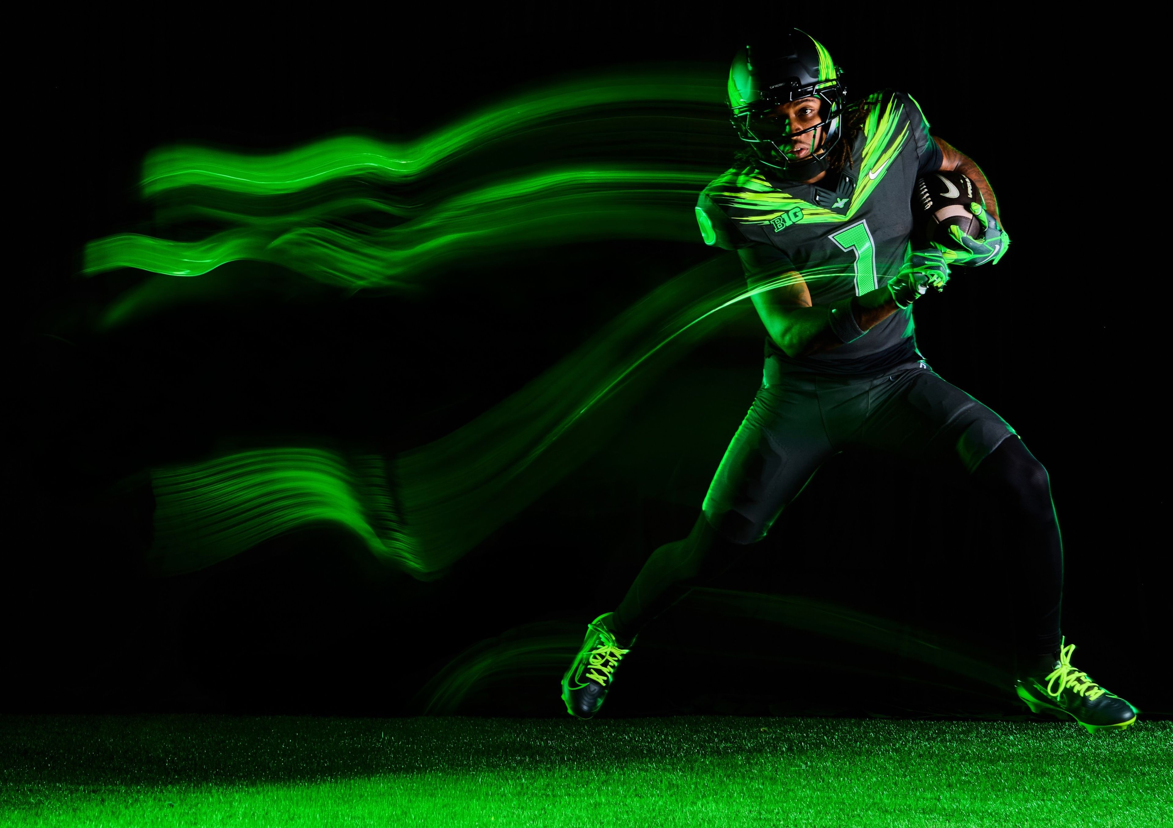 A football player in an Oregon Ducks uniform runs with the ball.