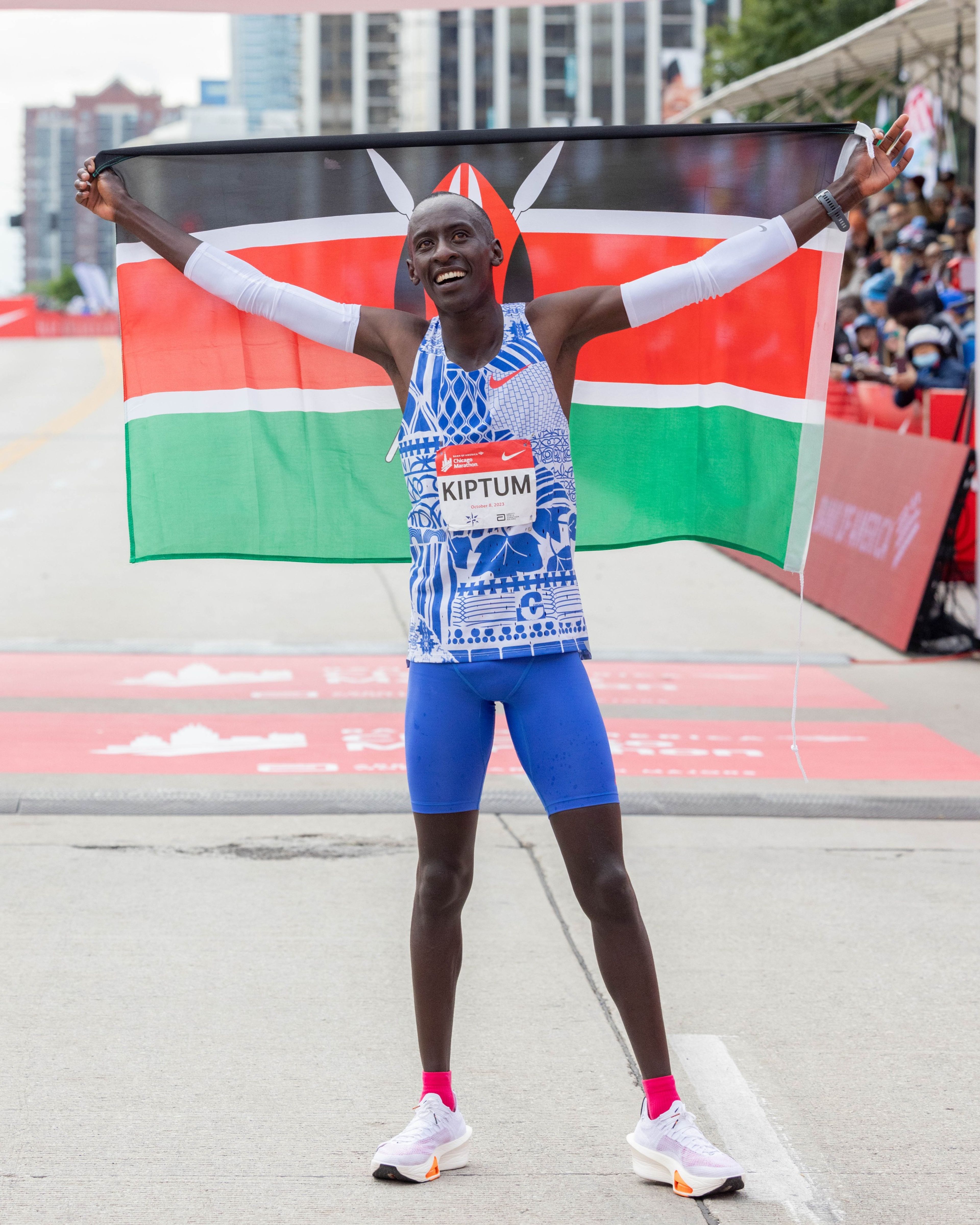 Kelvin Kiptum holding up the Kenyan flag behind him and wearing the Nike Alphafly 3 after setting the new marathon world record at the 2023 Chicago Marathon