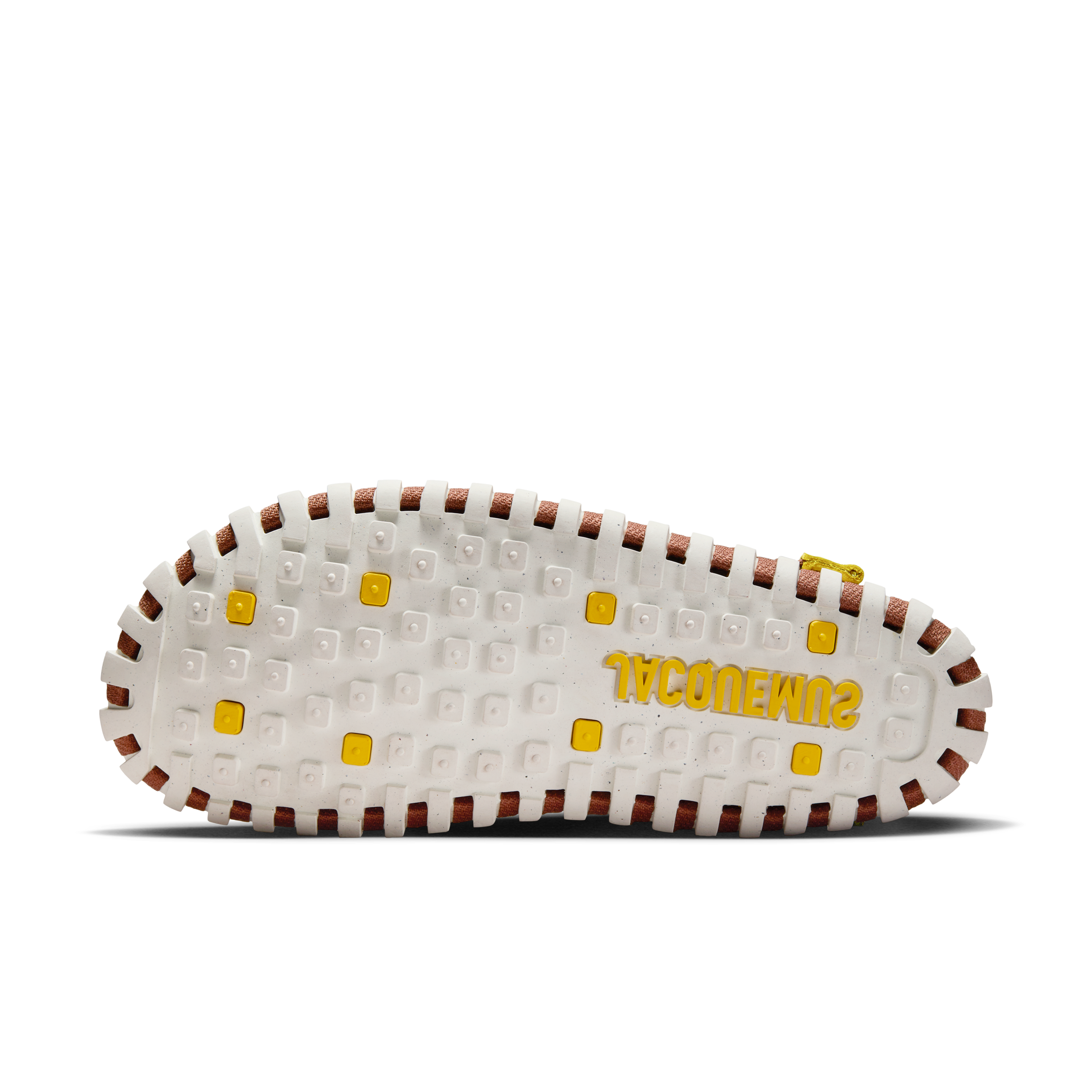 Underside view of a Nike x Jacquemus J Force 1 Low LX SP, with a white sole with yellow details, including yellow Jacquemus logo. We see brown webbing details where the shoe layers are held together. The shoe floats on a black background.