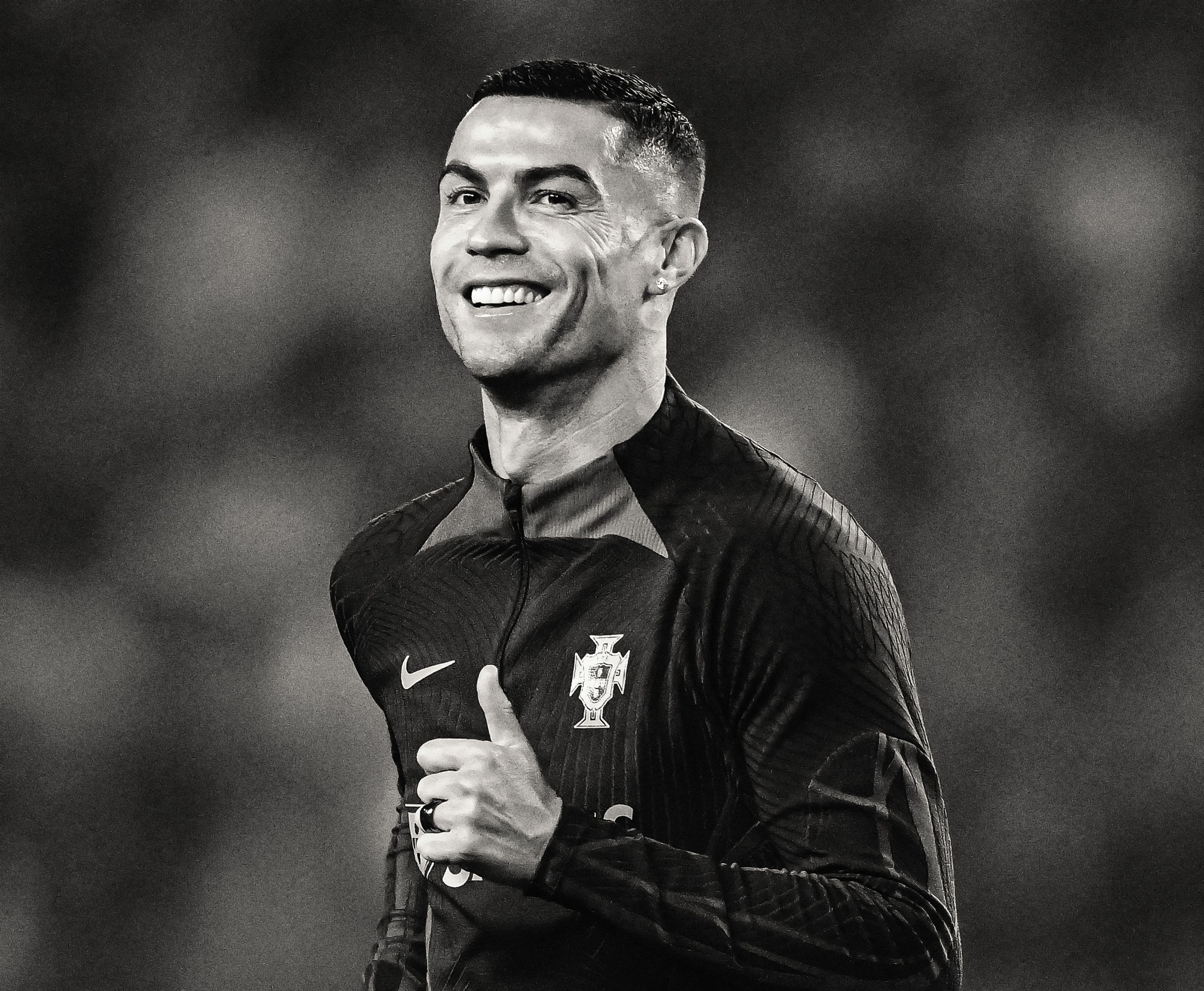 Black and white photo of Cristiano Ronaldo smiling and giving a thumbs up.
