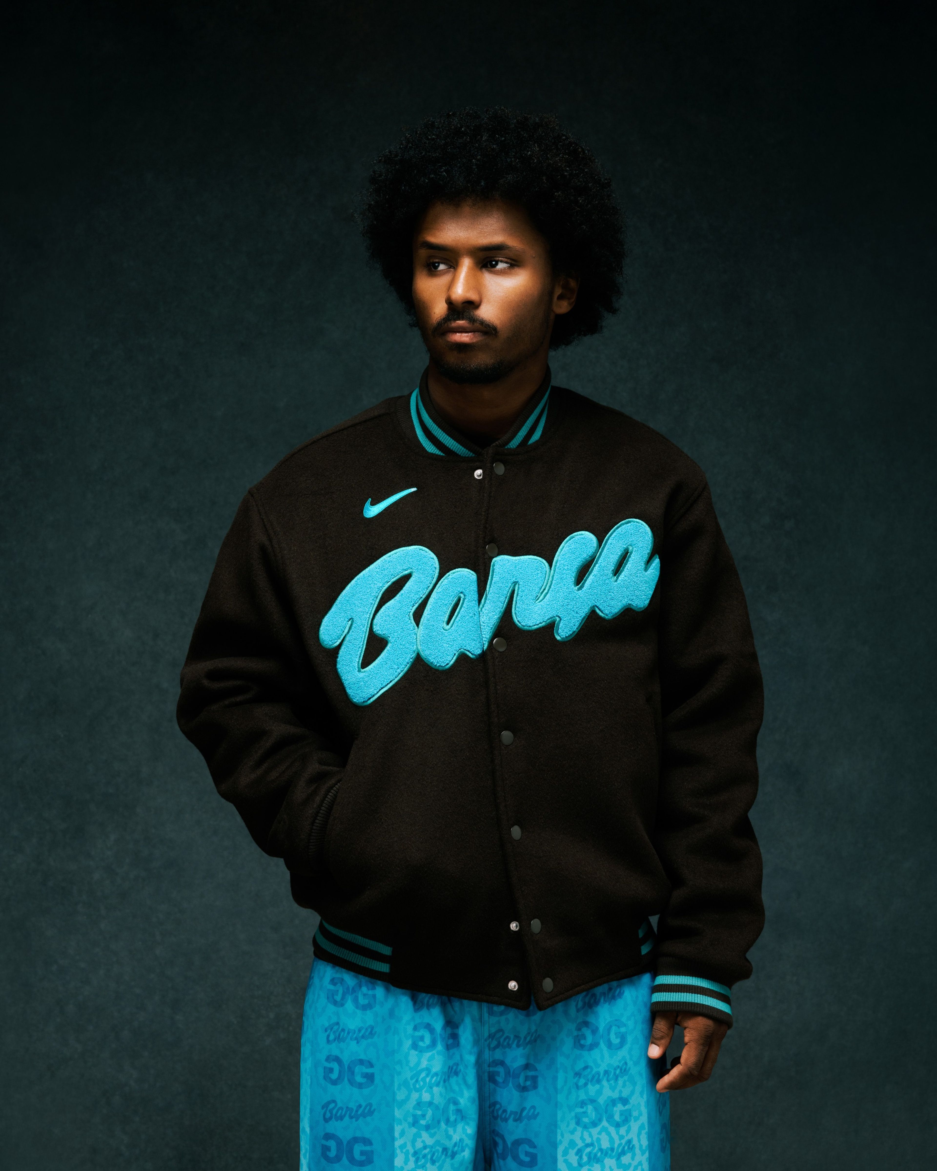 Person wearing Nike x FC Barcelona x GOLF WANG (GOLF) varsity jacket.