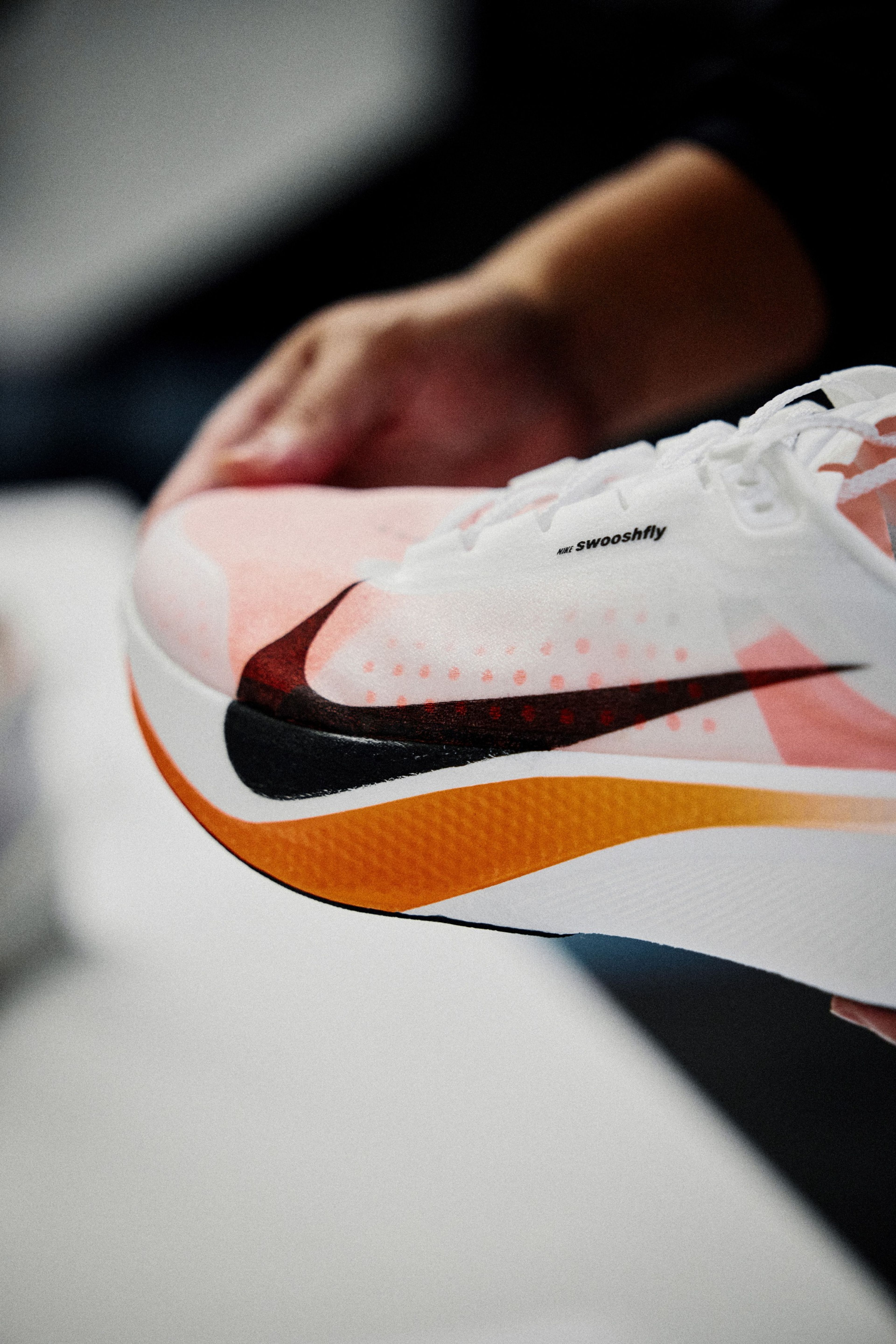 Nike Swoosh Fly running shoe with a black Swoosh held in front of a mostly white background