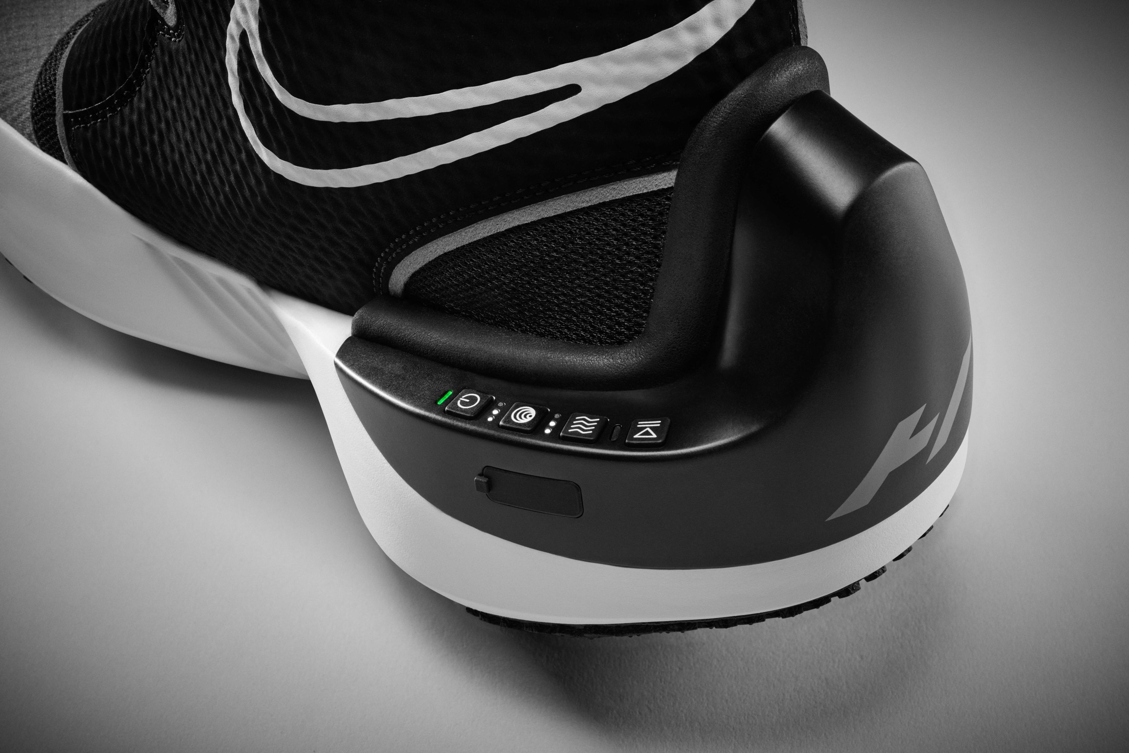 Detail view of Nike x Hyperice boot control features. 4 control buttons and charging port are integrated into the control feature of the boot. Boot sits on a grey background.
