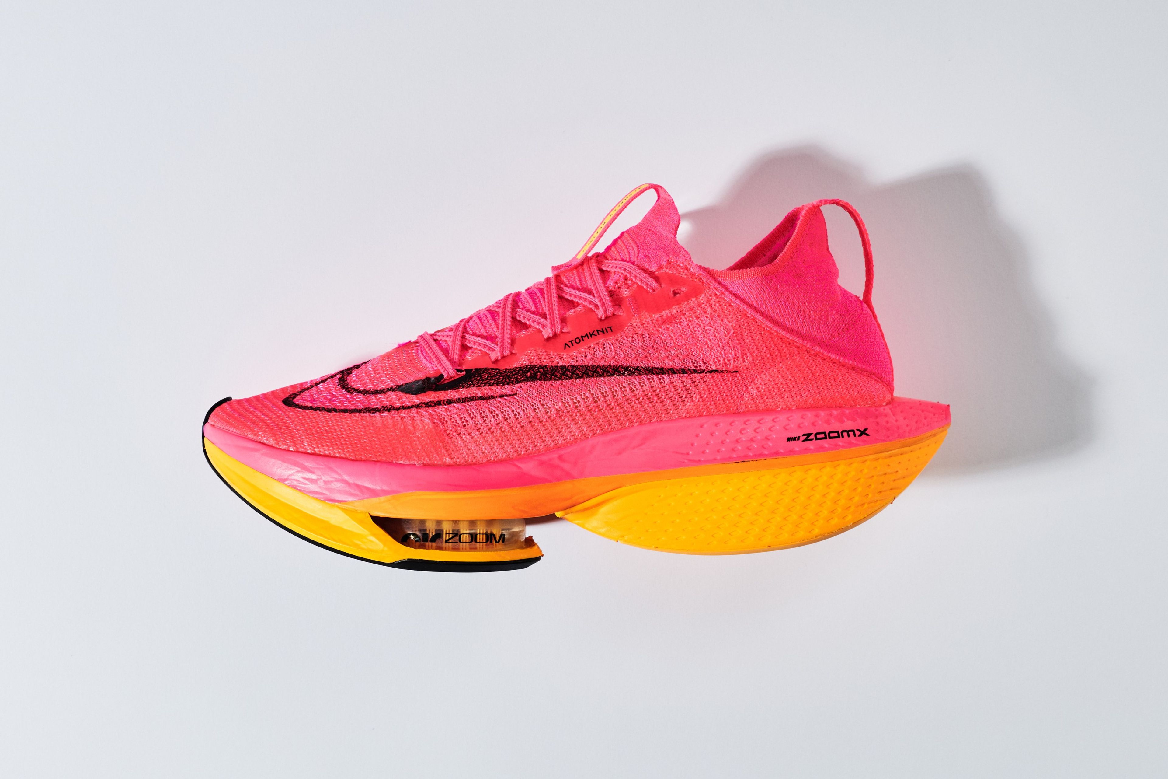 Nike Air Zoom Alphafly NEXT% 2 running shoe in pink Atomknit upper with black Swoosh, orange ZoomX midsole, and visible Air Zoom pod.