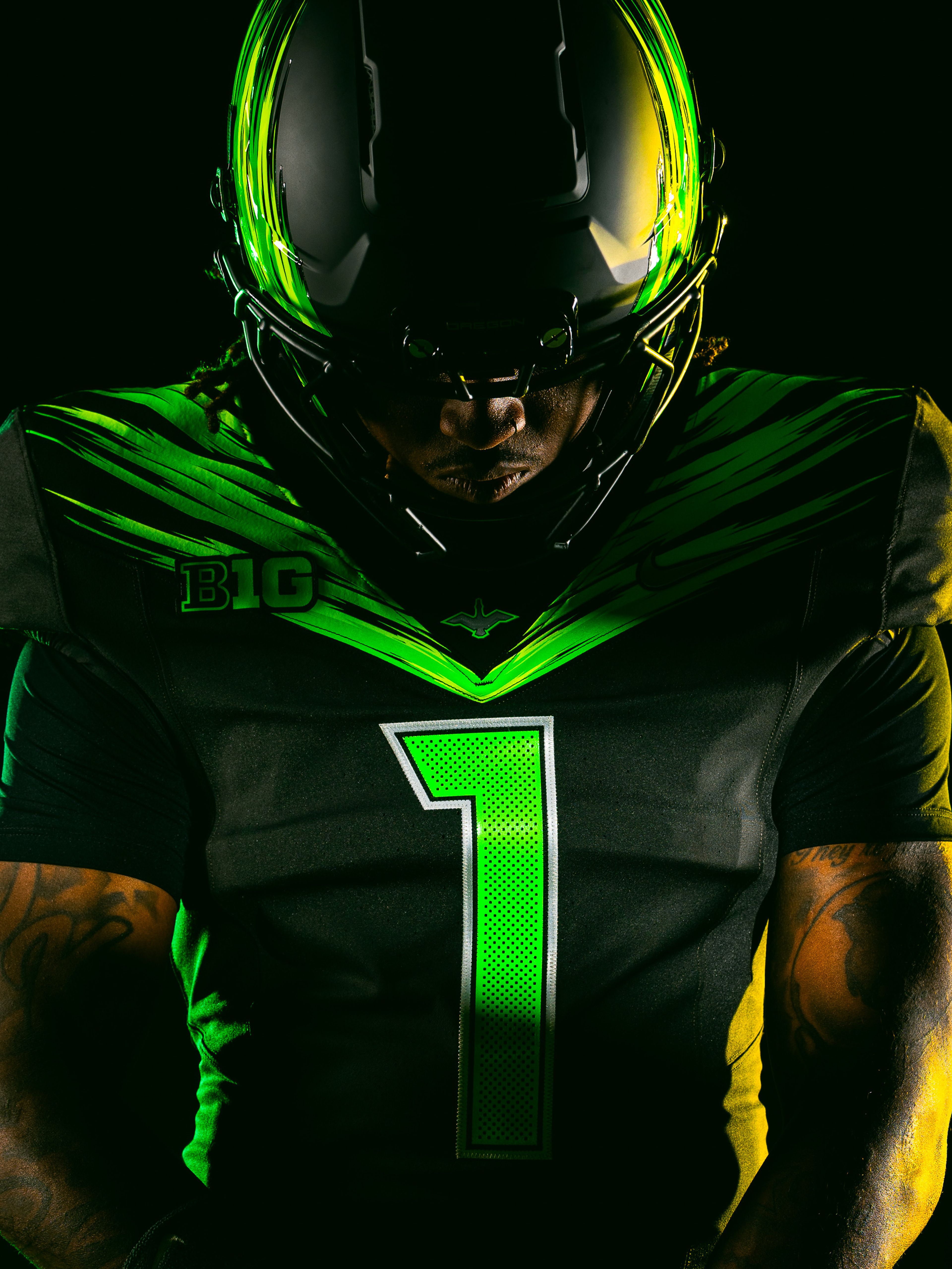 A football player in an Oregon Ducks uniform wearing a reflective helmet with wing details.
