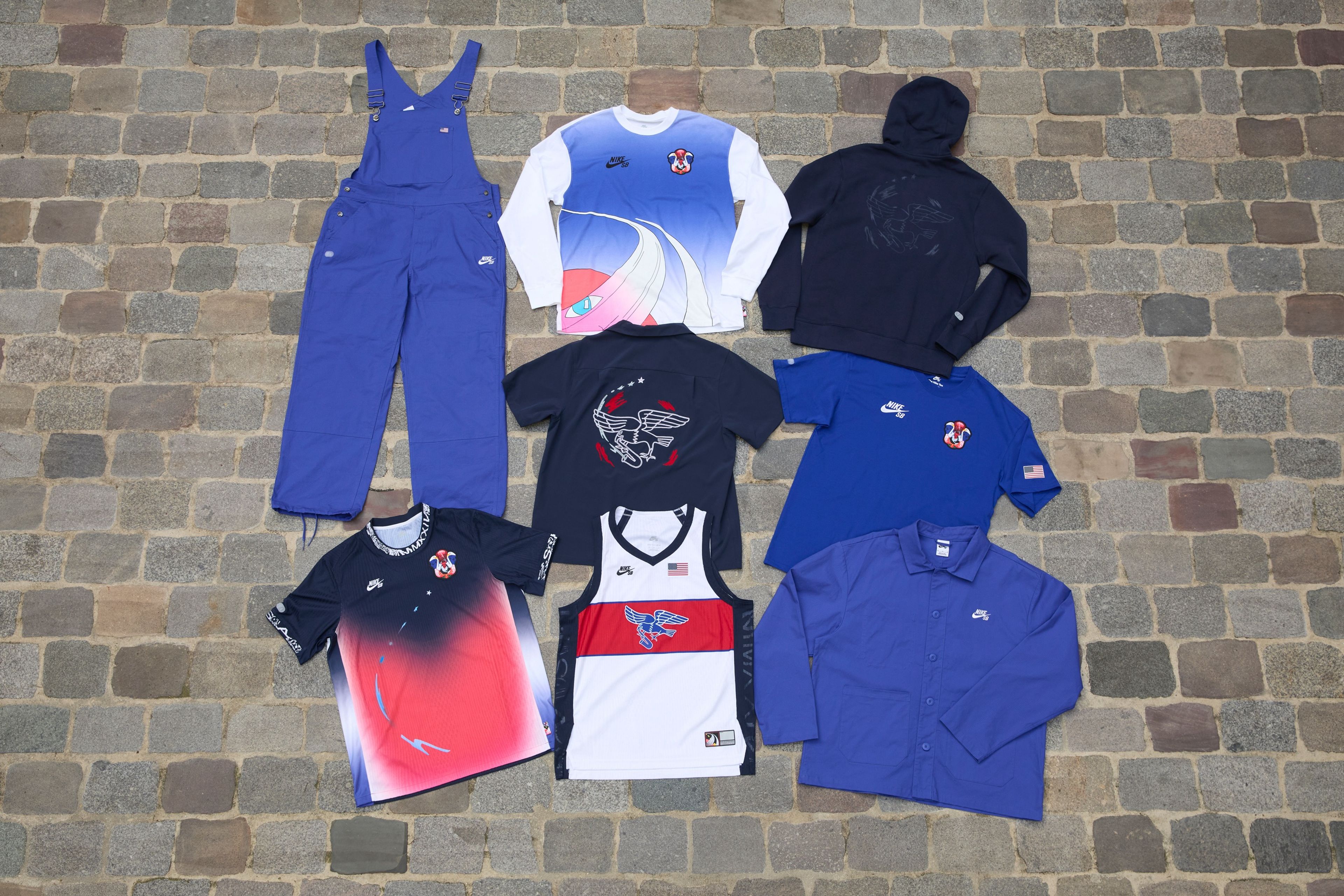 Overhead view of seven pieces of clothing items from the skateboarding federation kits for the USA olympic team.