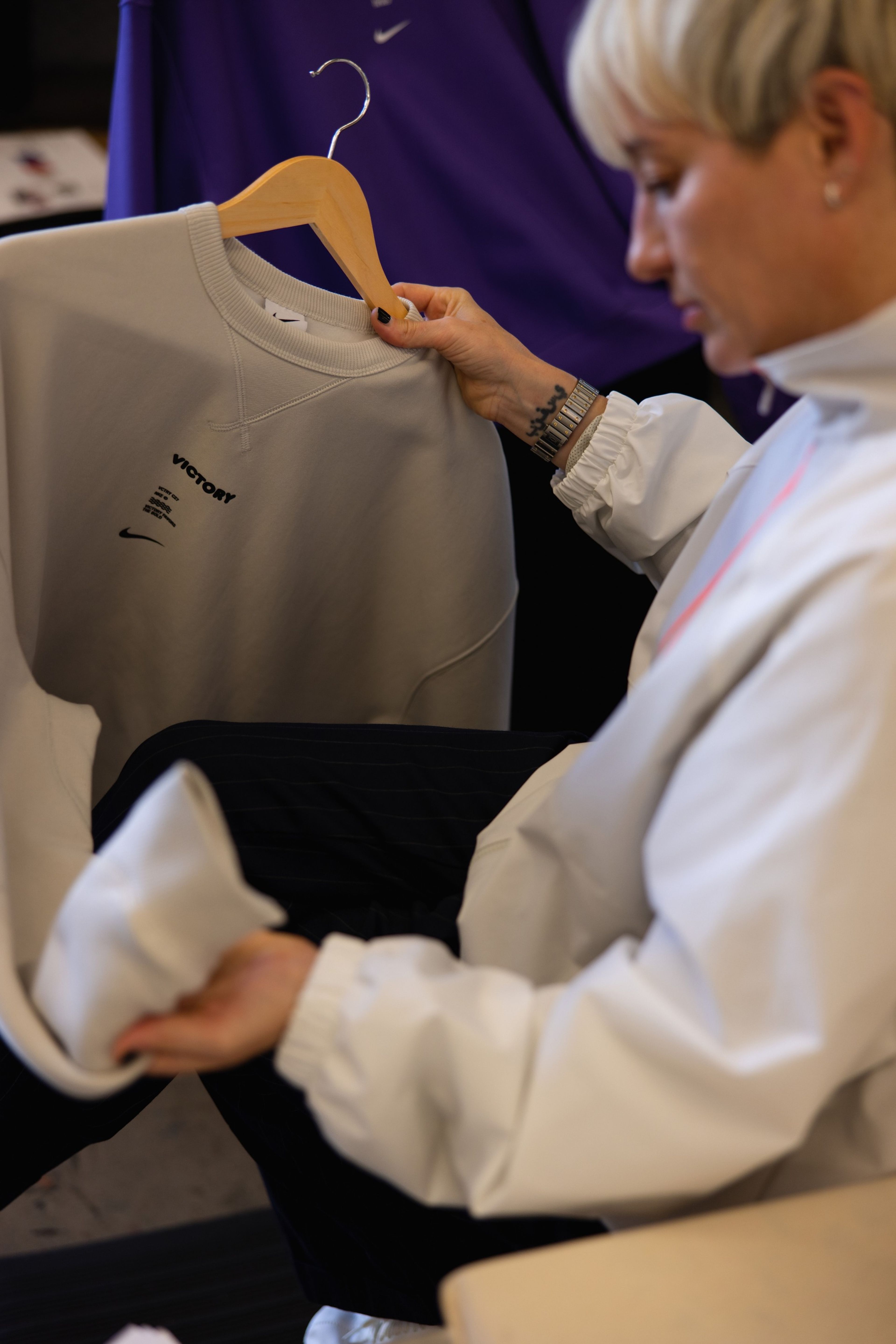 A woman examines a grey Nike Victory Collection sweatshirt