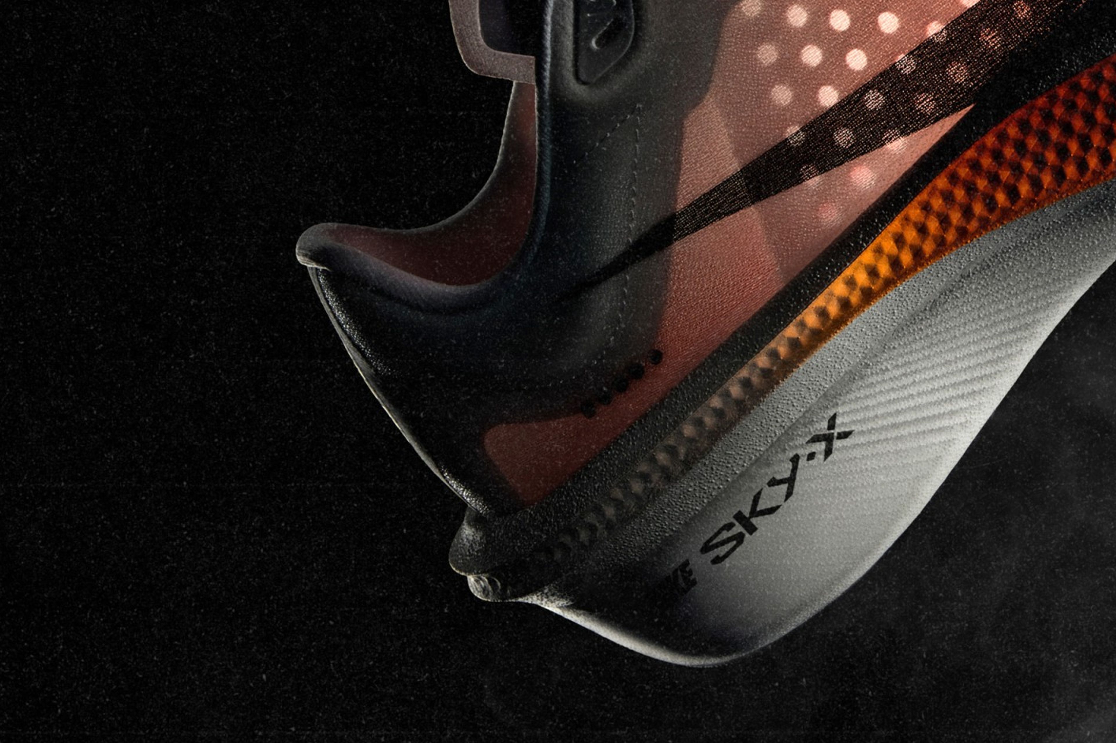 Nike Swooshfly running shoe with translucent upper and black Swoosh floating against a dark background.