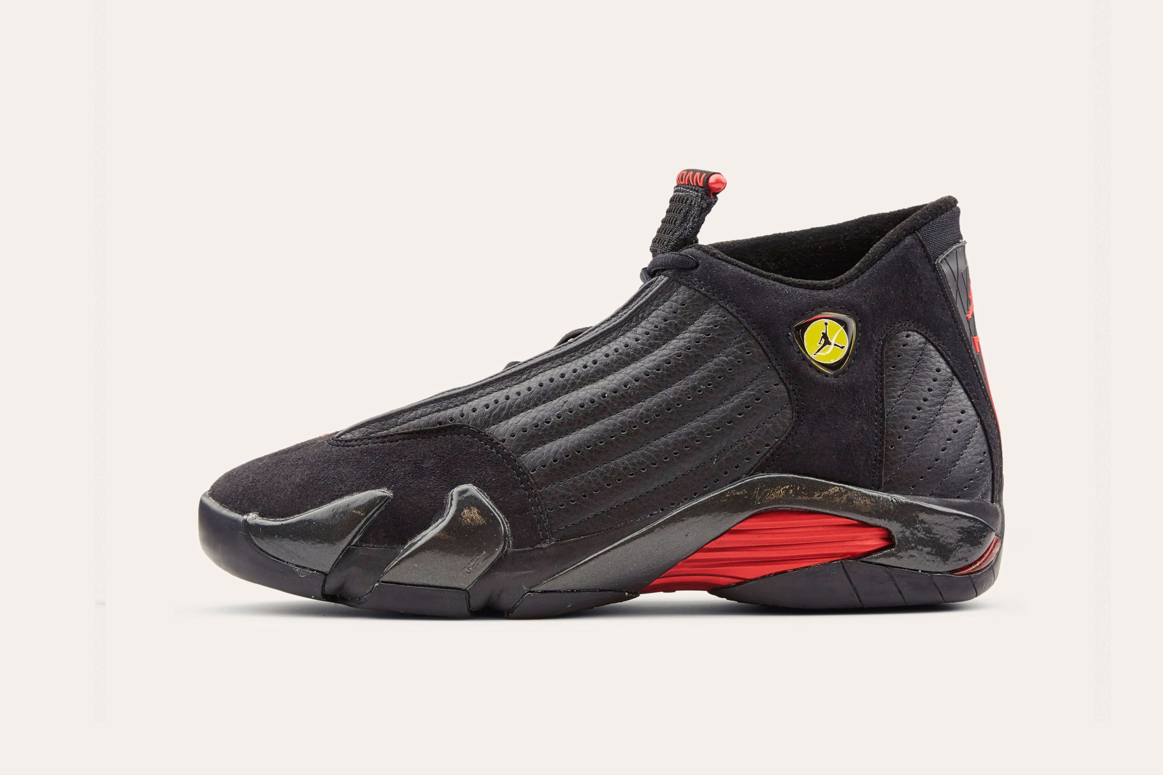 A black Nike sneaker with an Air Jordan emblem on the side of the cuff and a red arch in the sole.