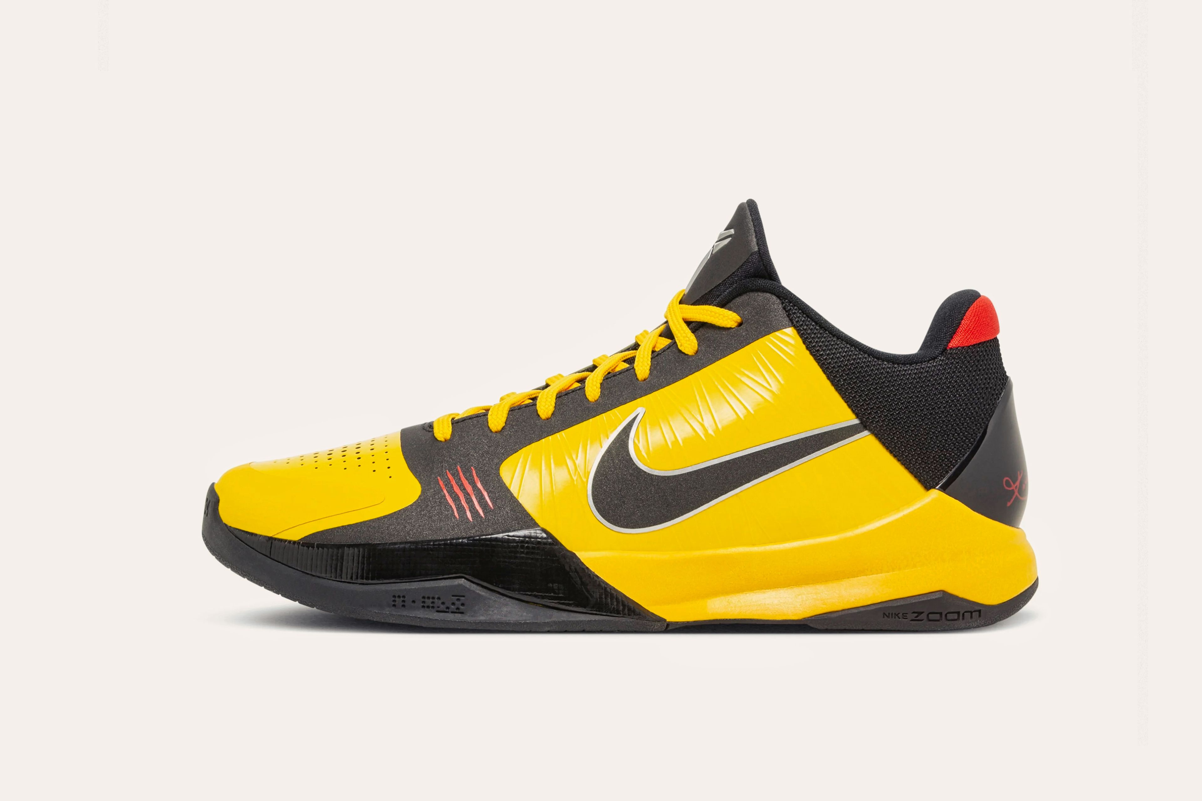 A dark grey sneaker with yellow laces, a yellow toecap, yellow siding with a dark grey Nike swoosh, and a red rear cuff.