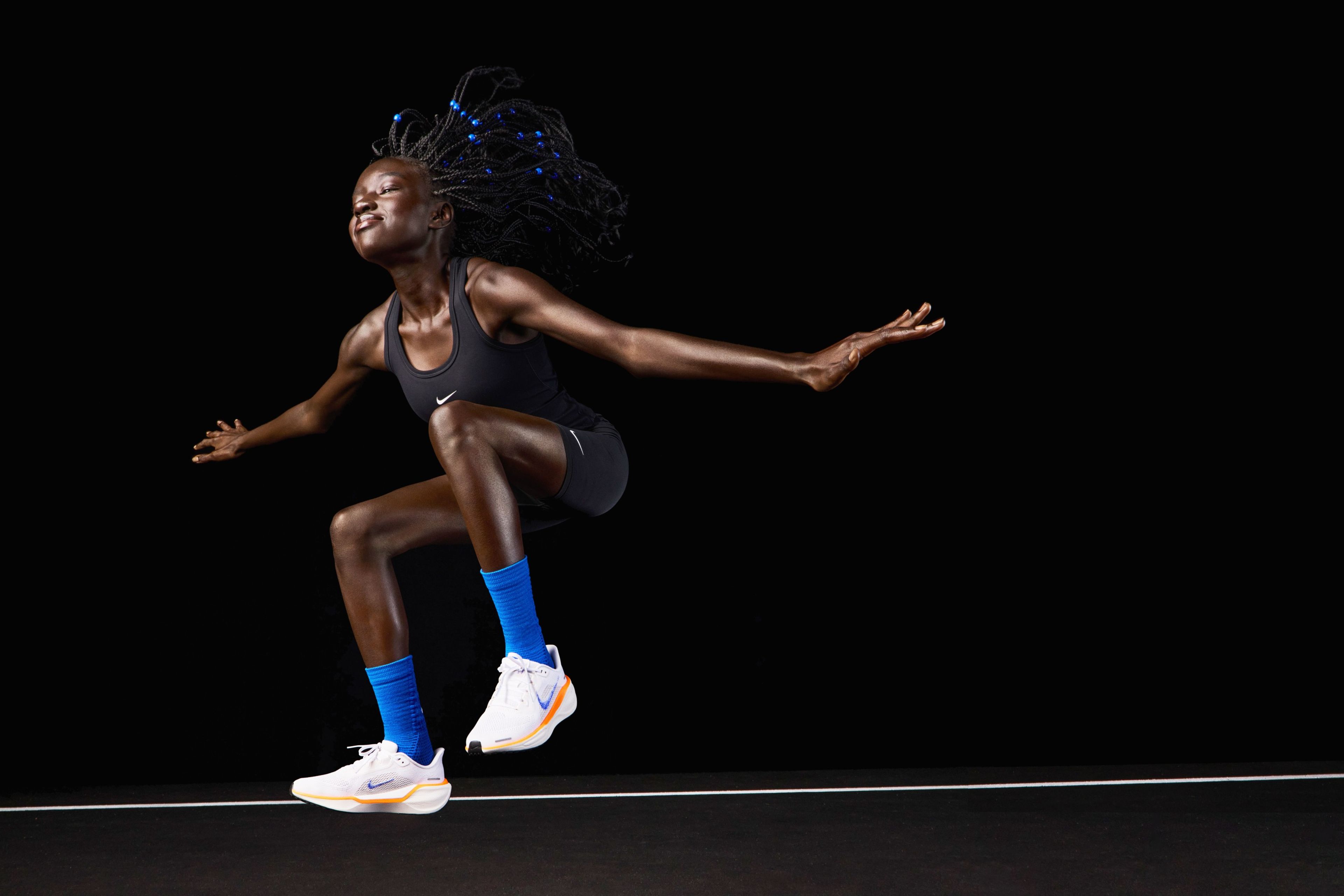 American 800 meter runner Akouc Chany wearing the Nike Pegasus 41 while jumping in air with her hands outstretched and her eyes closed.