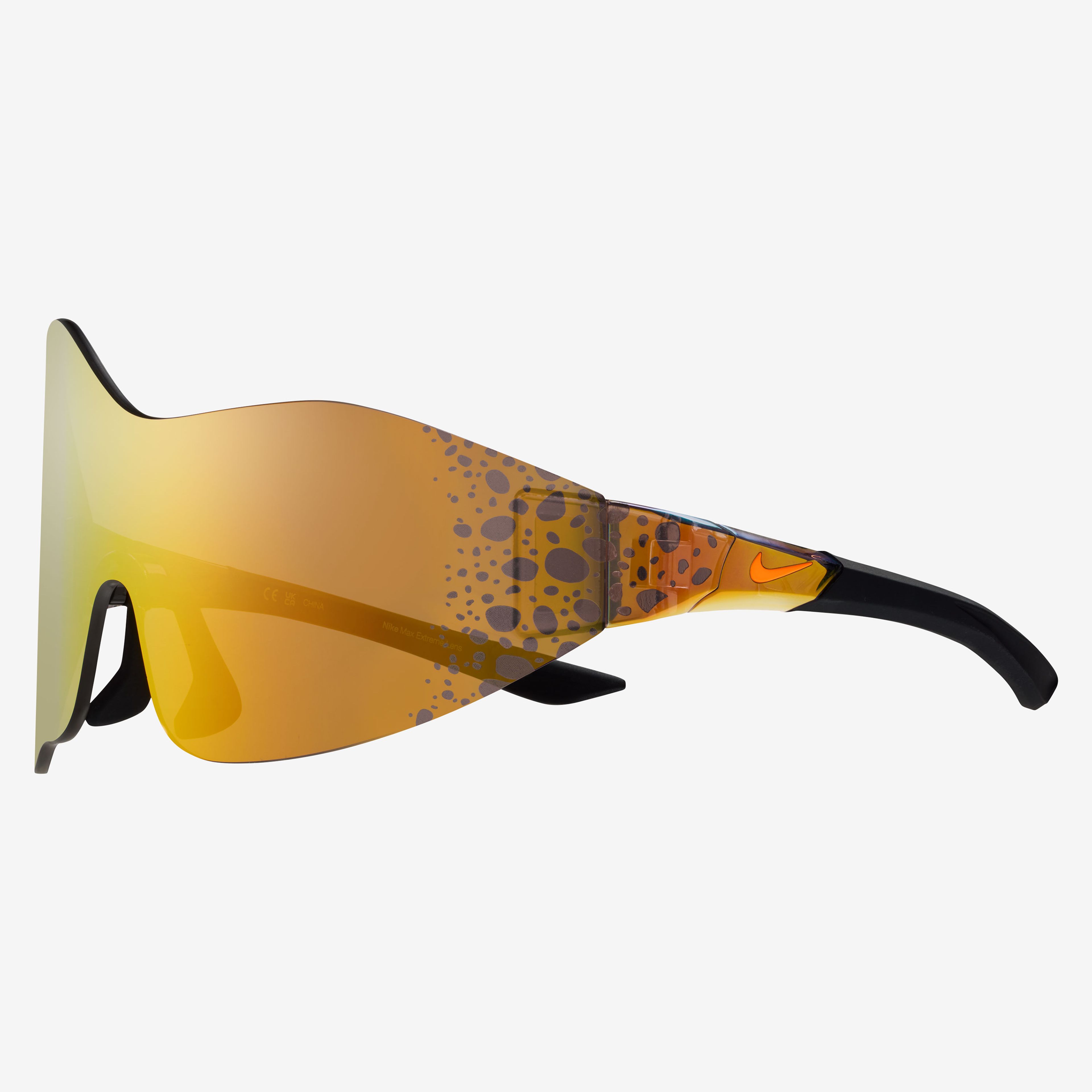 Side view of the Nike Athena sunglasses, showcasing the wrapping asymmetrical mirrored orange lens with Electric graphic at the temples. Electric graphic is a pattern of brown/black speckled spots. Glasses float on a white background.