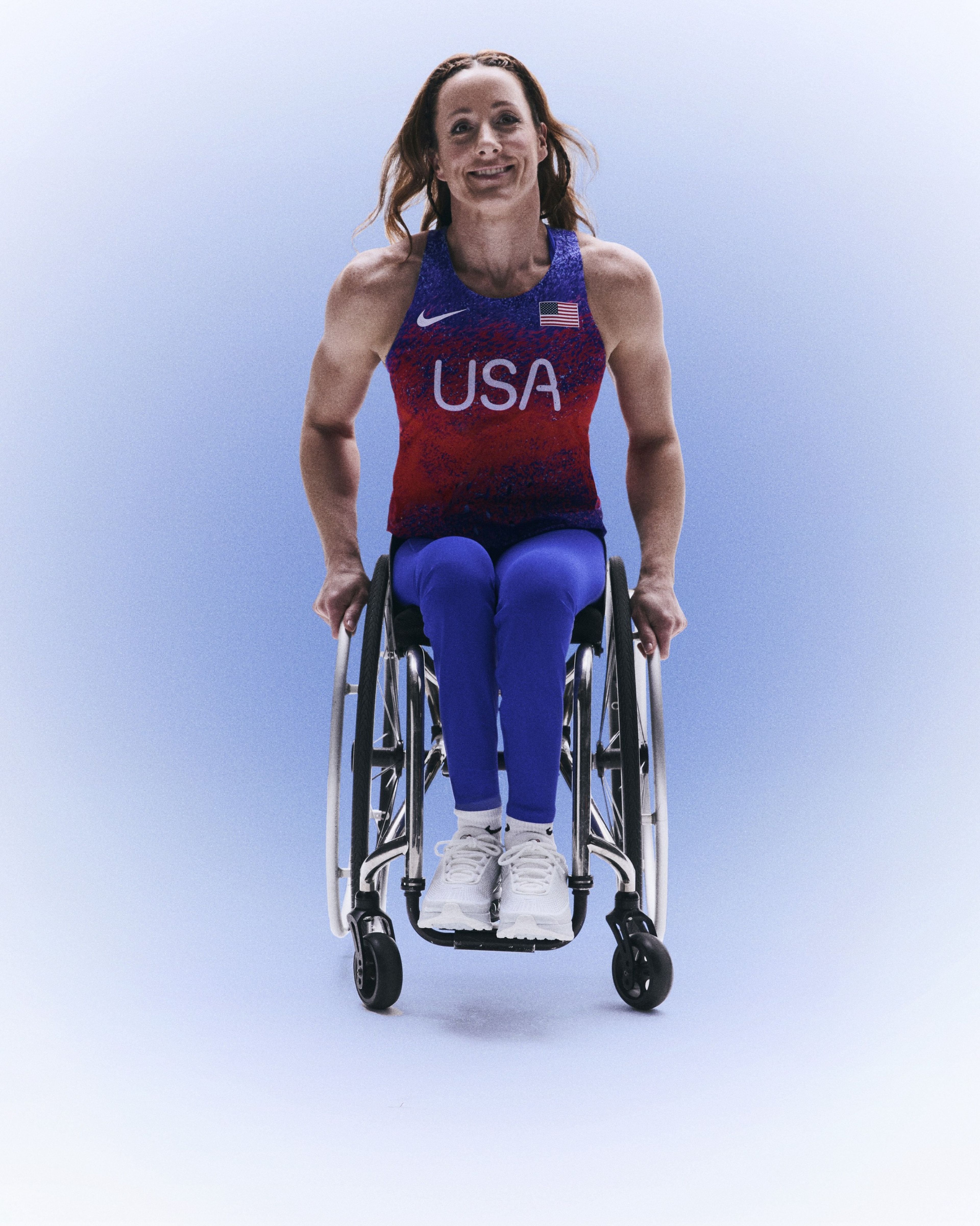 Tatyana McFadden smiling in her wheelchair while wearing her USA track and field kit uniform.