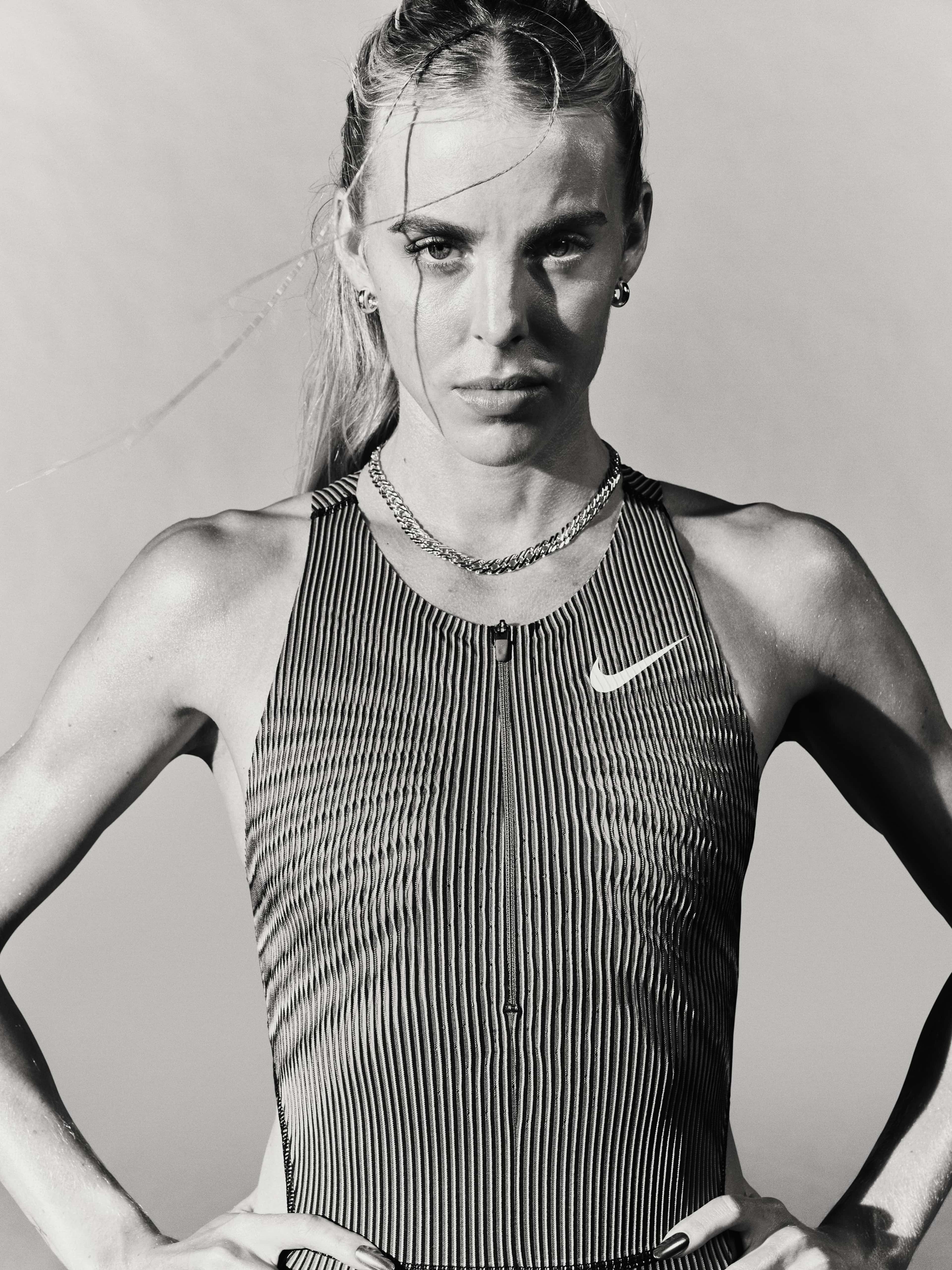 Black and white photo of Keely Hodgkinson, wearing a Nike runnining tank and holding her hands on her hips.