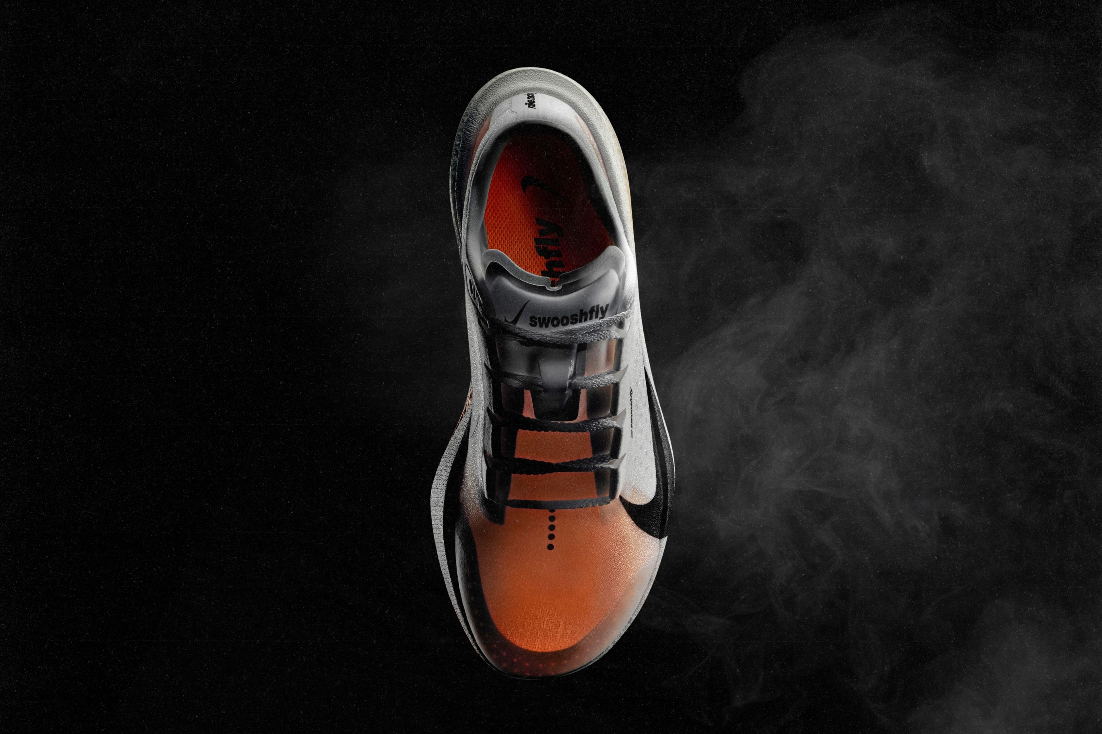 Top-down view of a Nike Swooshfly running shoe with black Swoosh against a dark background.