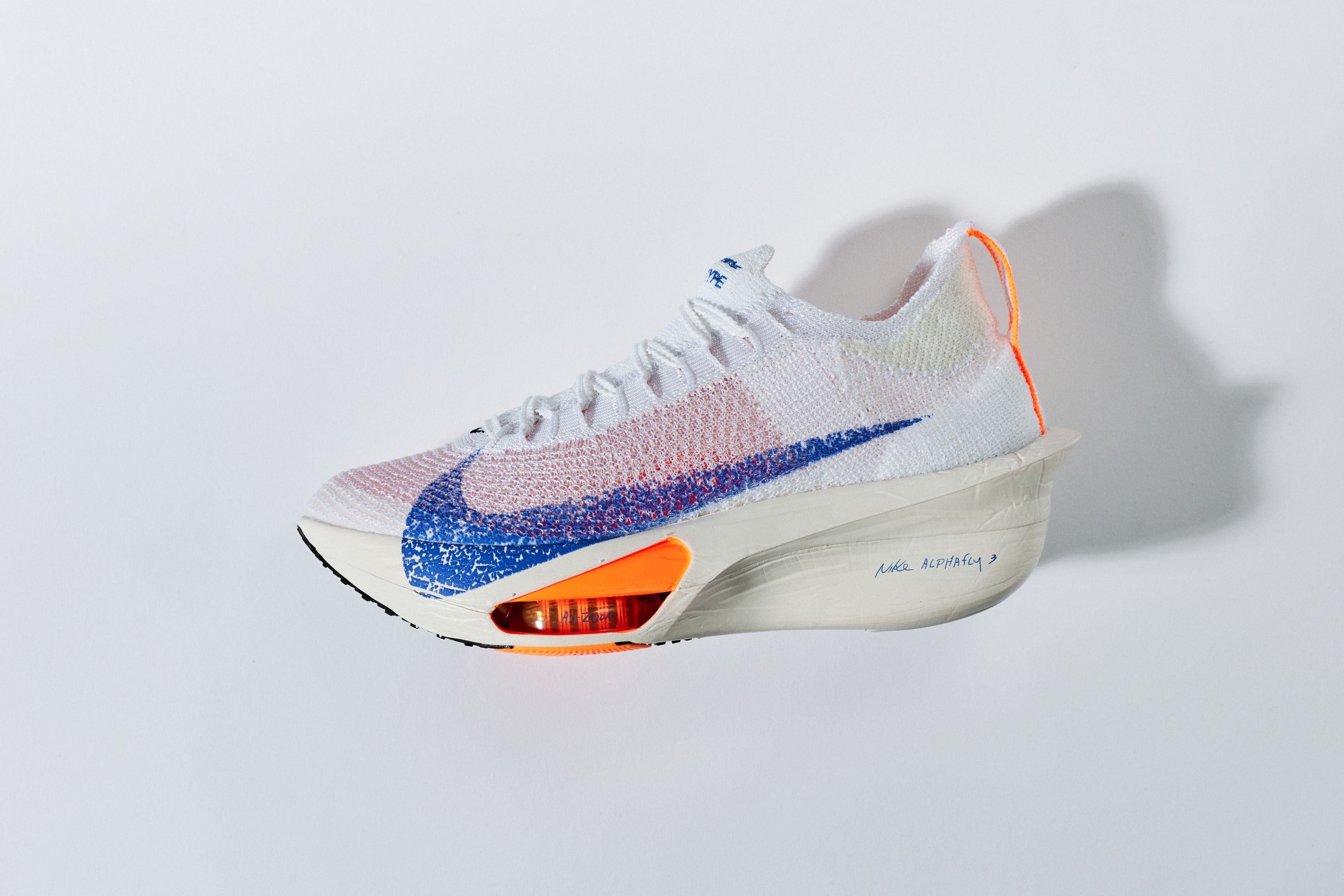 Nike Alphafly 3 running shoe in white with blue and orange accents, shown in profile against a light grey background.