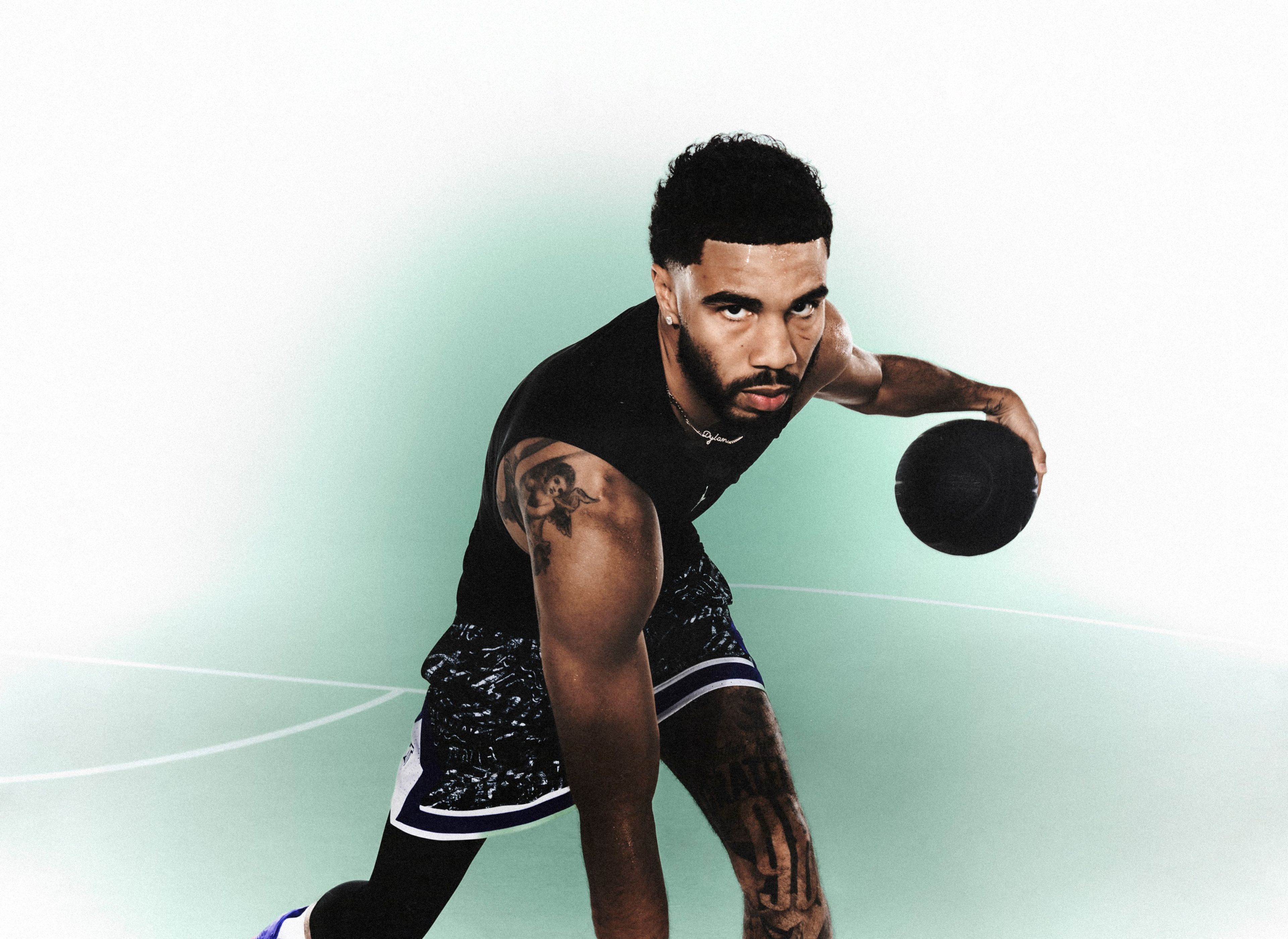 Jordan Brand athlete Jayson Tatum dribbles a basketball in front of a green and white background.