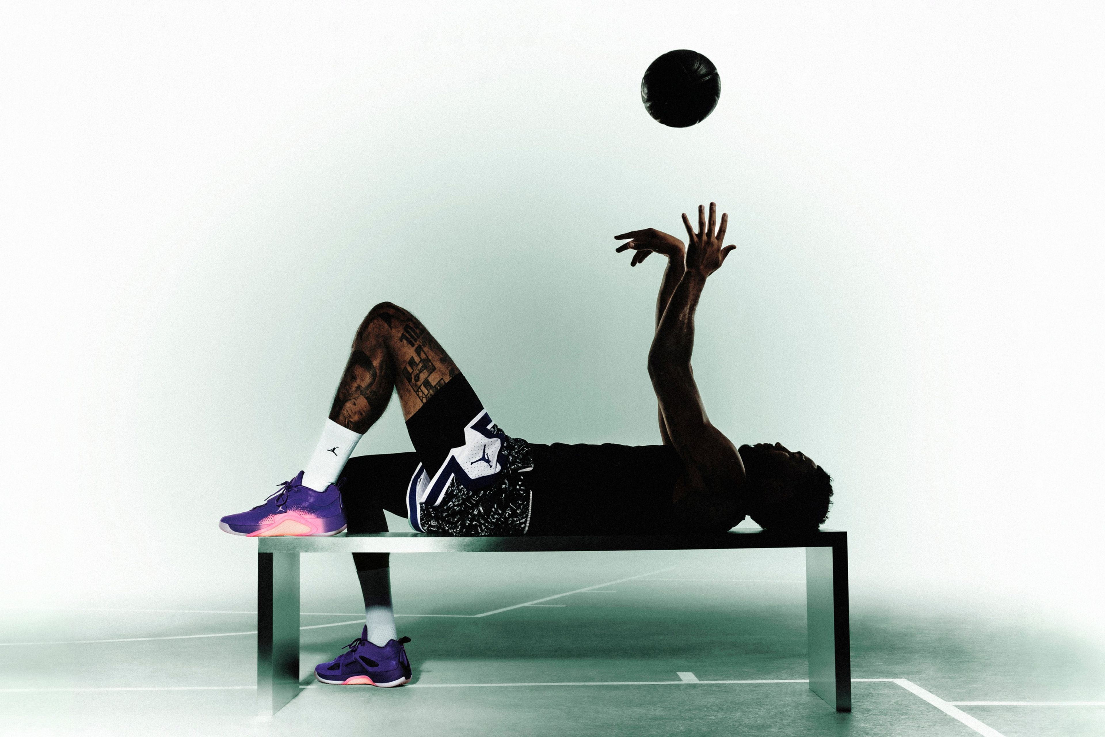 Jordan Brand athlete Jayson Tatum lays on a table, tossing a basketball into the air while wearing his new Tatum 5 signature shoe.