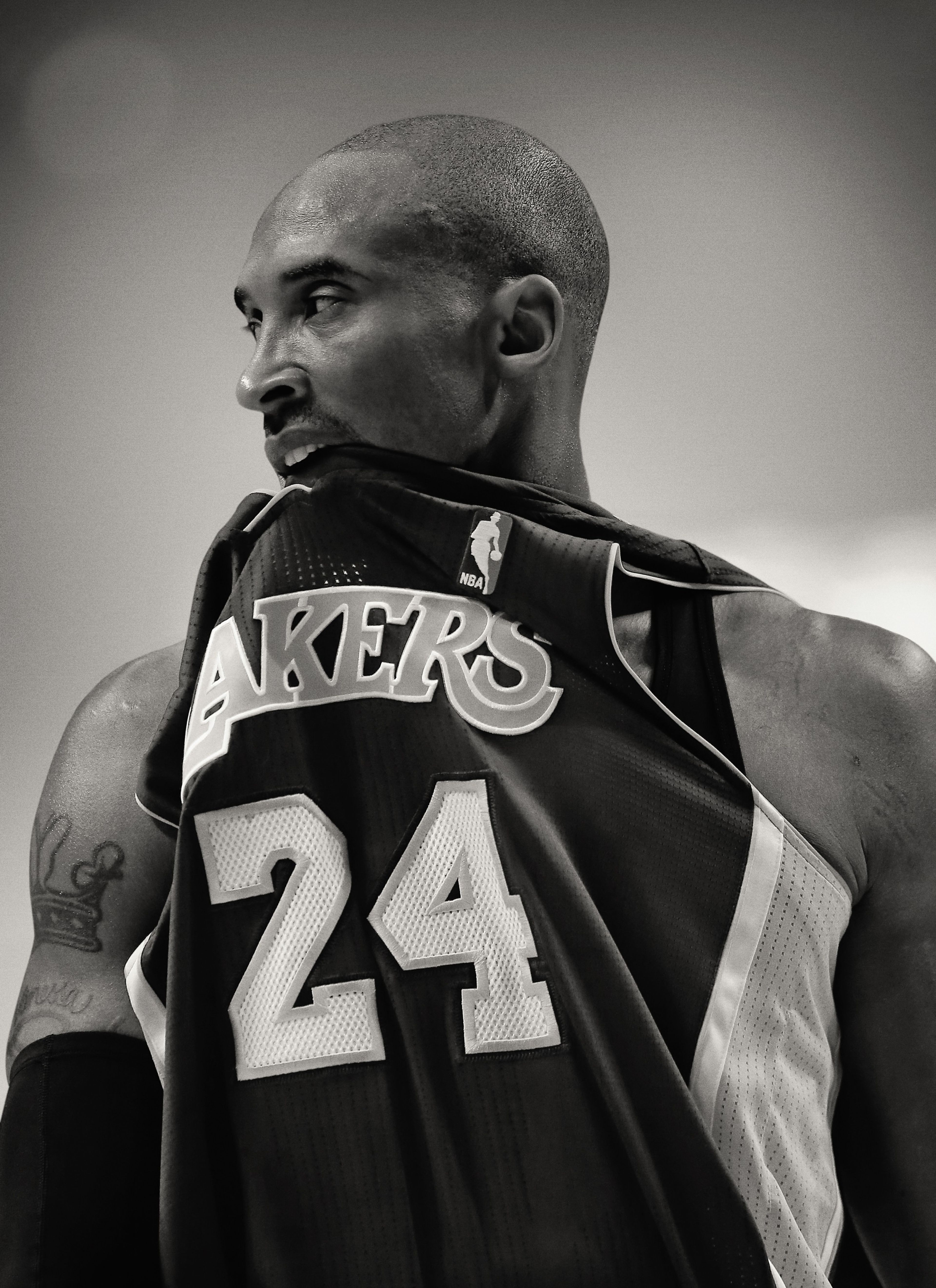 Black and white photo of Kobe Bryant biting the front collar of his jersey.