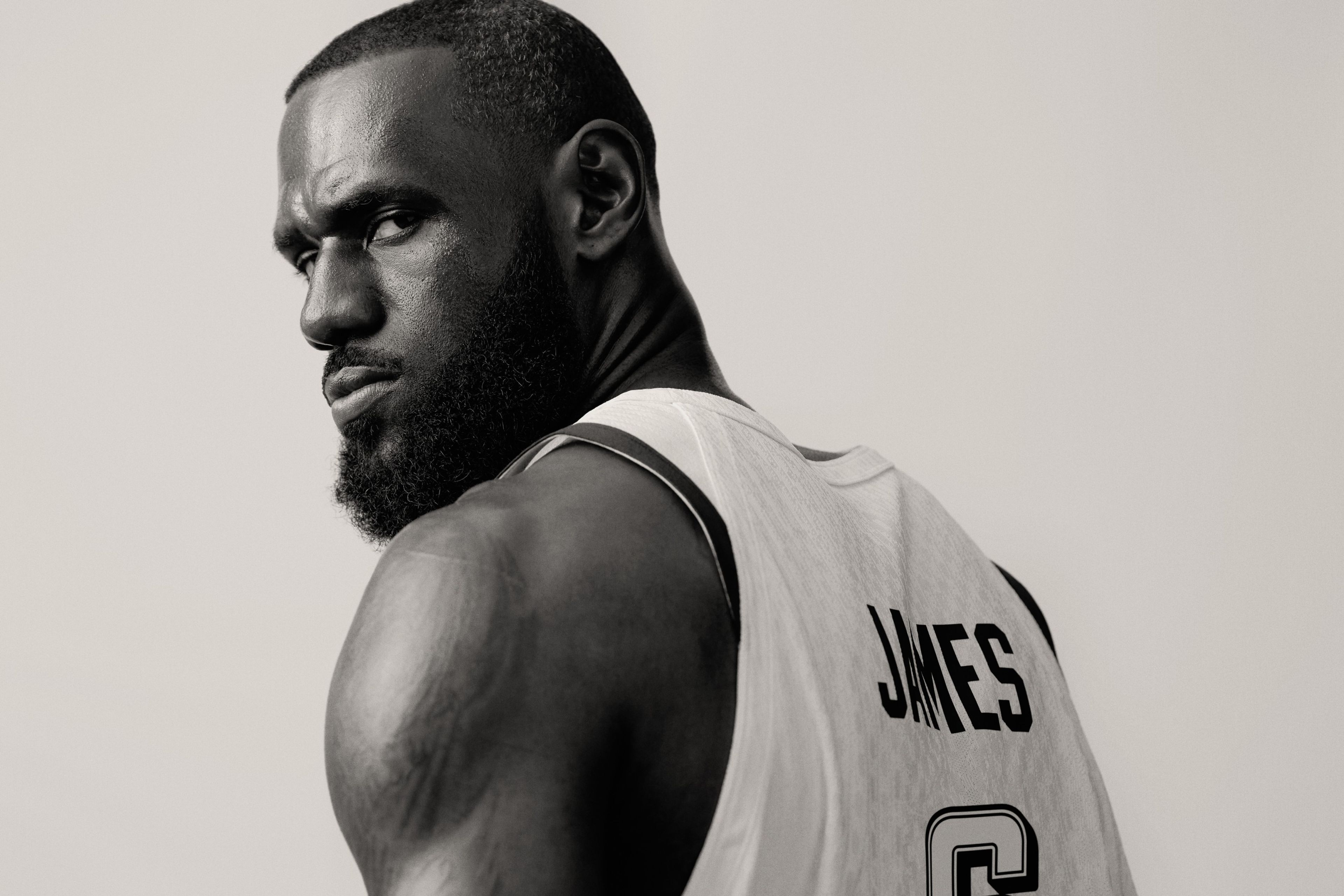 Black and white close up of Lebron James looking back over his shoulder at the camer. He wears his Team USA jersey with James appearing on the back.