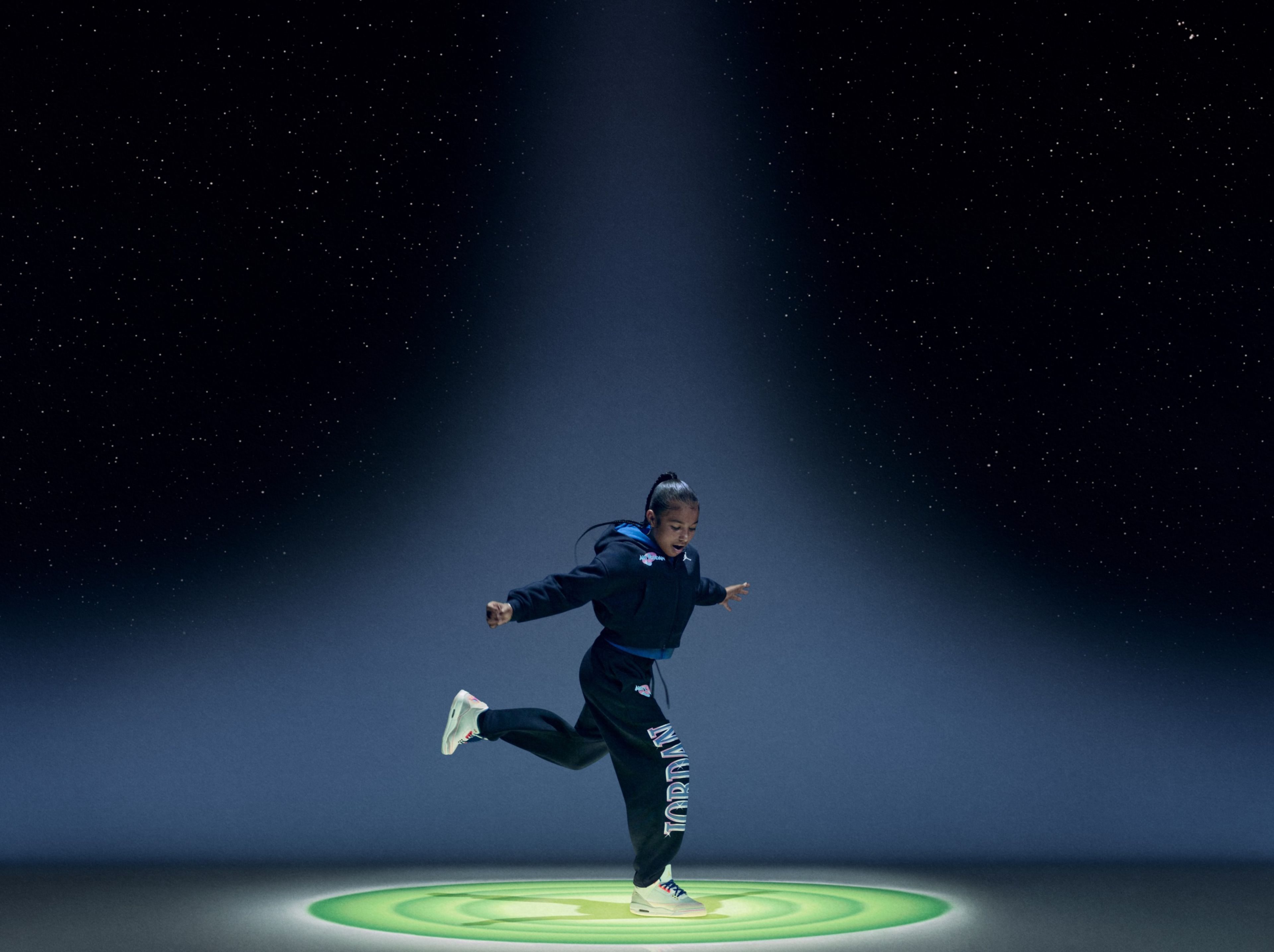 A young dancer mid-movement wearing black Jordan Brand x Space Jam apparel.