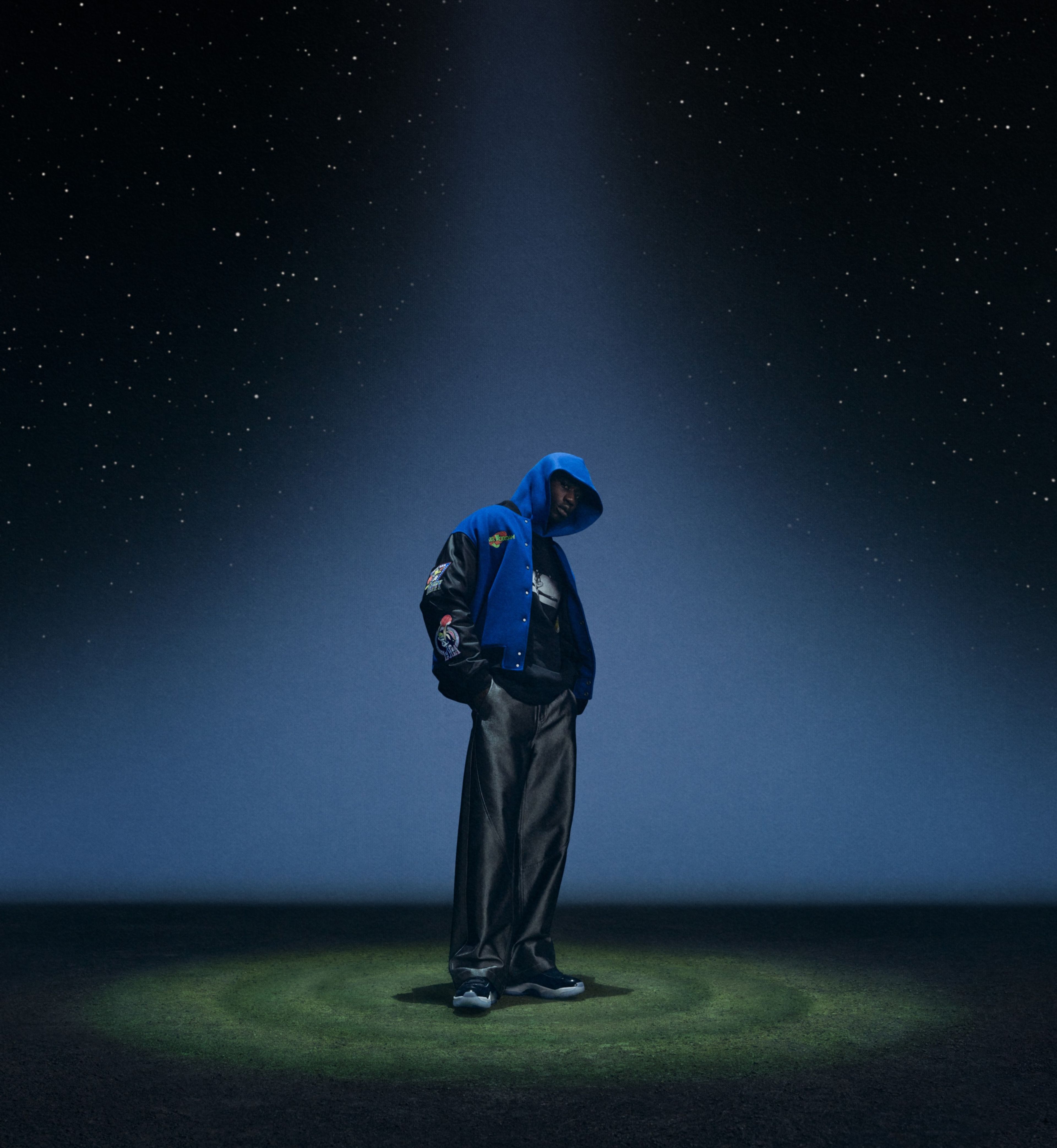 The Jordan Brand x Space Jam varsity jacket, featuring a relaxed Jordan fit, faux-wool construction, retro patches, trading card–inspired graphics, a Monstars-influenced galaxy lining, and a “secret stuff”-inspired interior label
