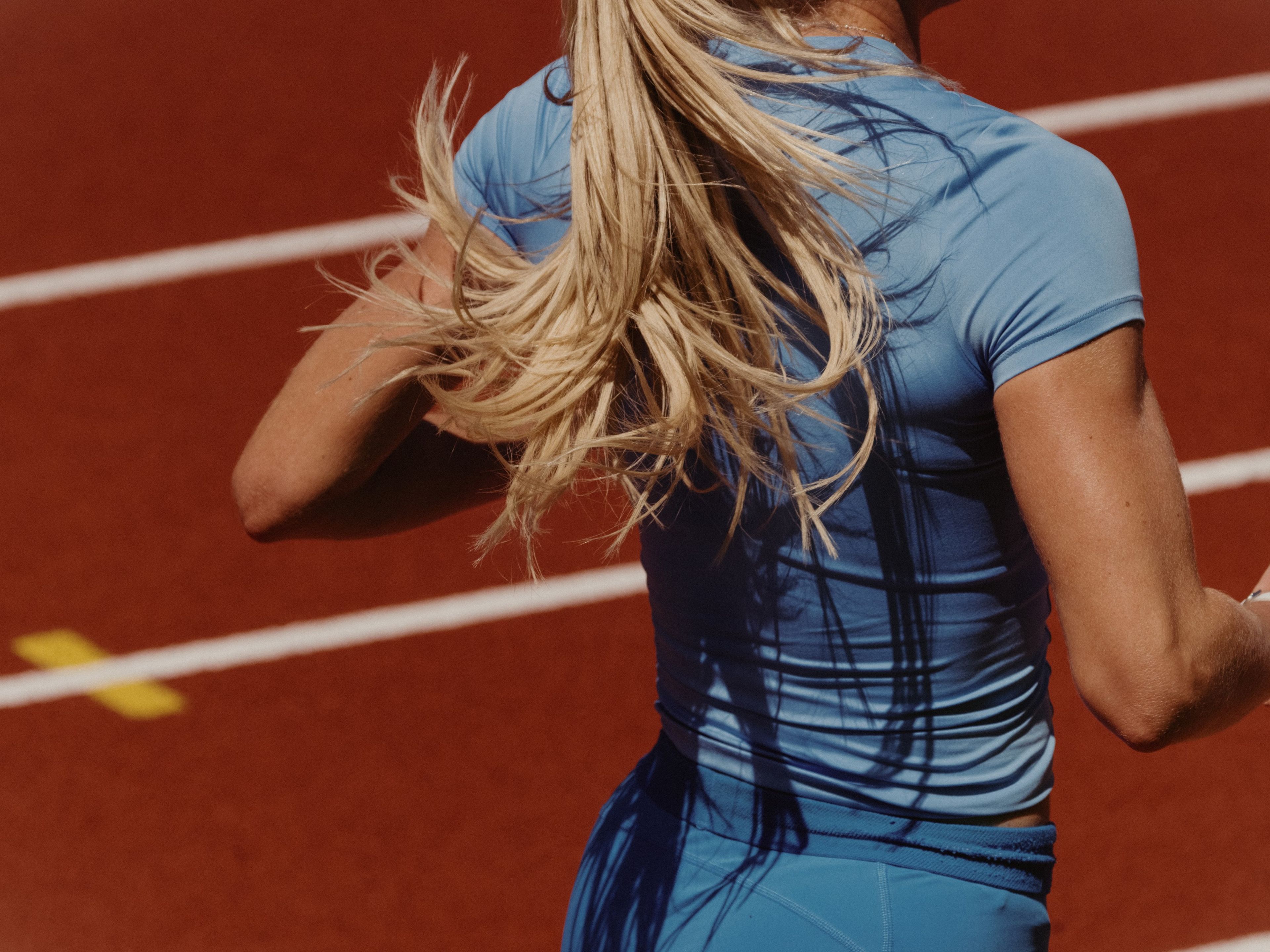 Keely Hodgkinson wears a blue top and shorts as she runs away from the camera during a race on a track.