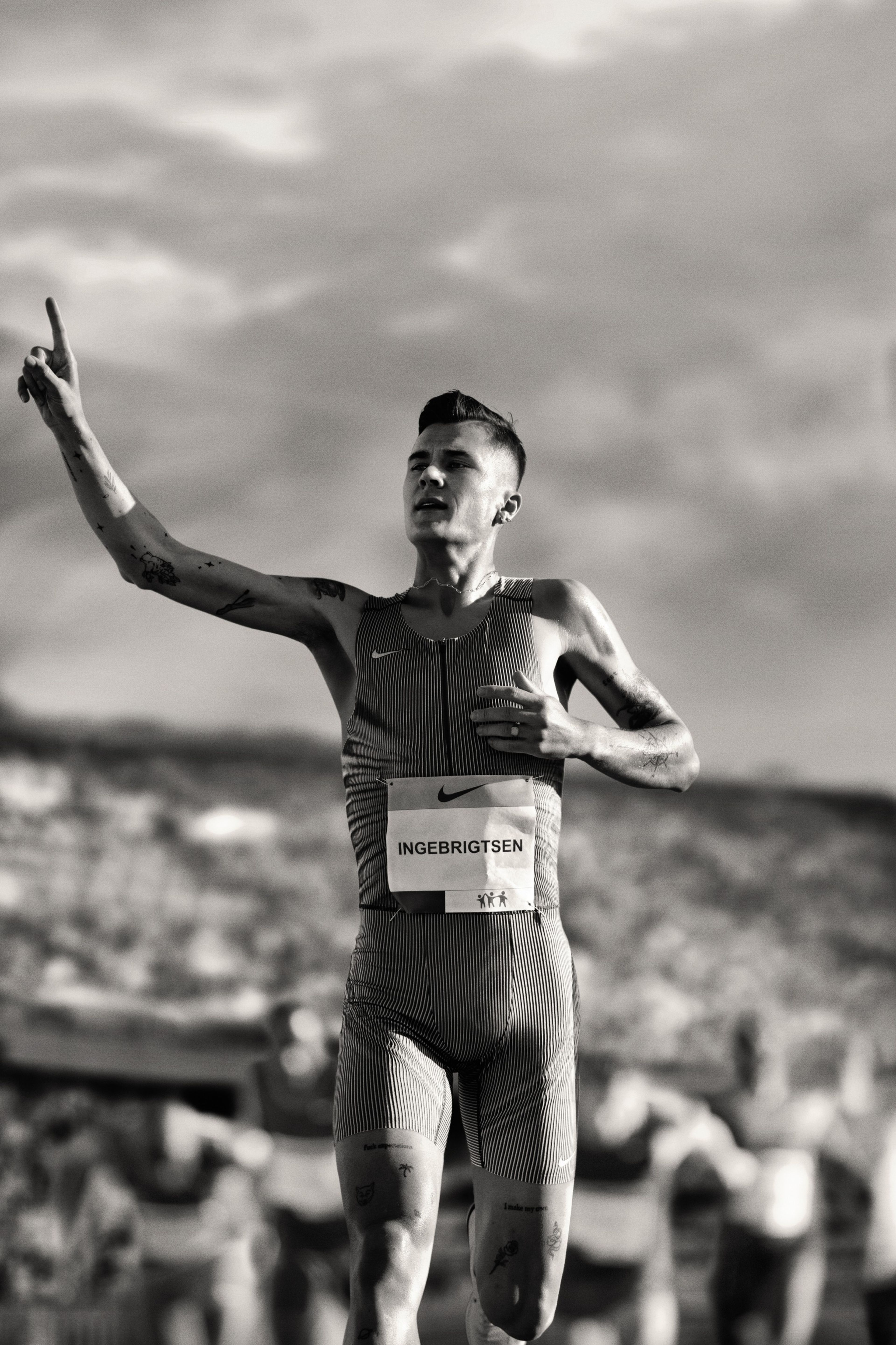 Black and white photo of Jakob Ingebrigtsen triumphantly holding up one finger at a running competition.