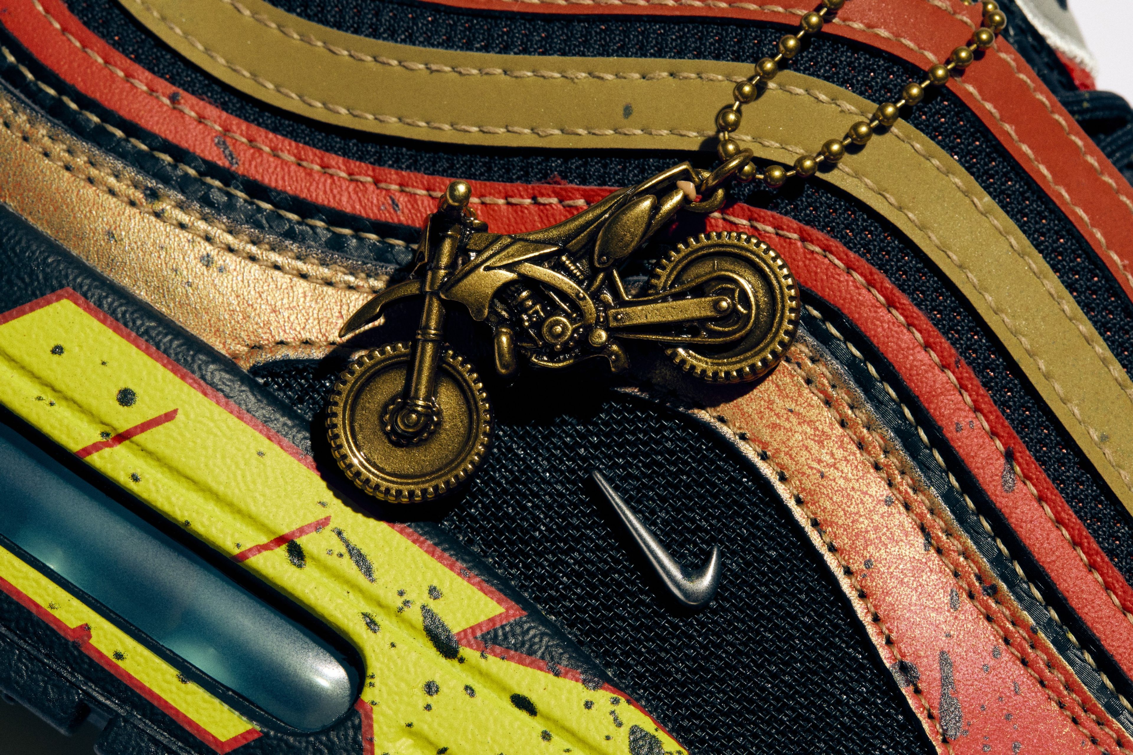 A brass dirt bike charm on Owen’s Air Max 1/97.