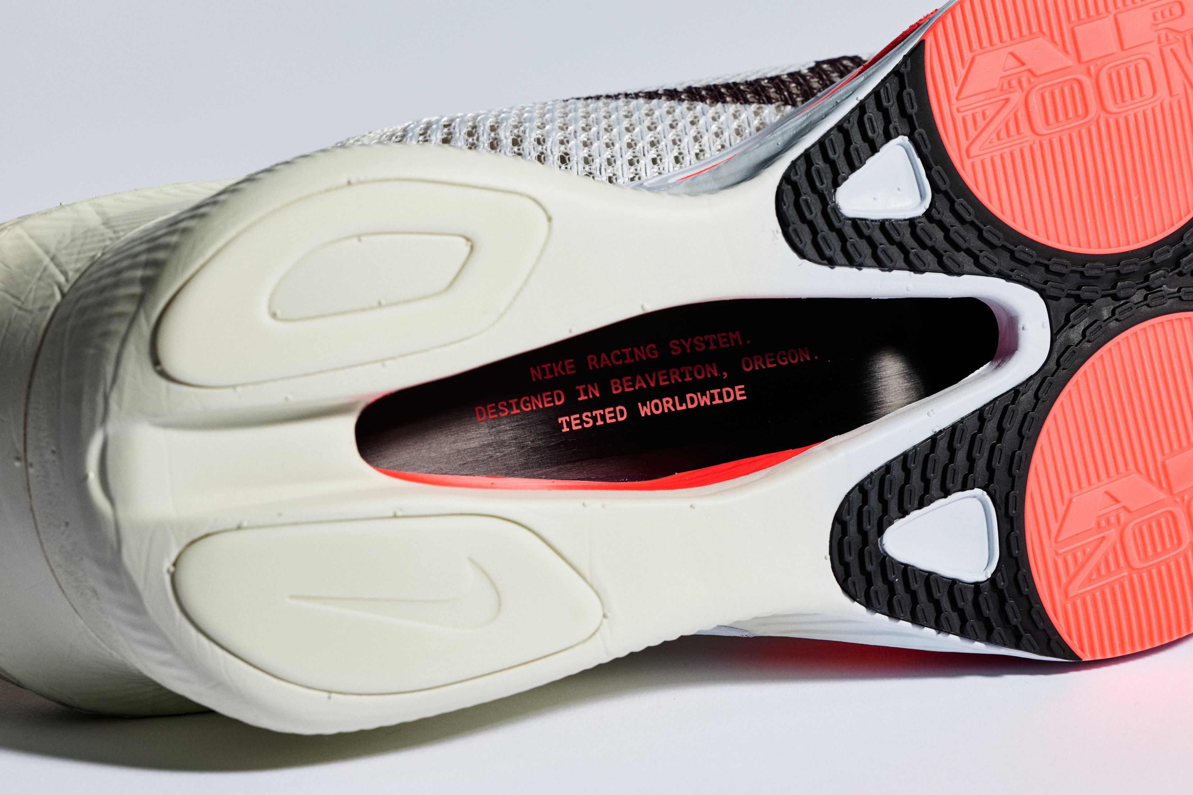 Sole of the Nike Alphafly 4 with white foam midsole, coral outsole, and insole text reading Designed in Beaverton, Oregon, Tested Worldwide.