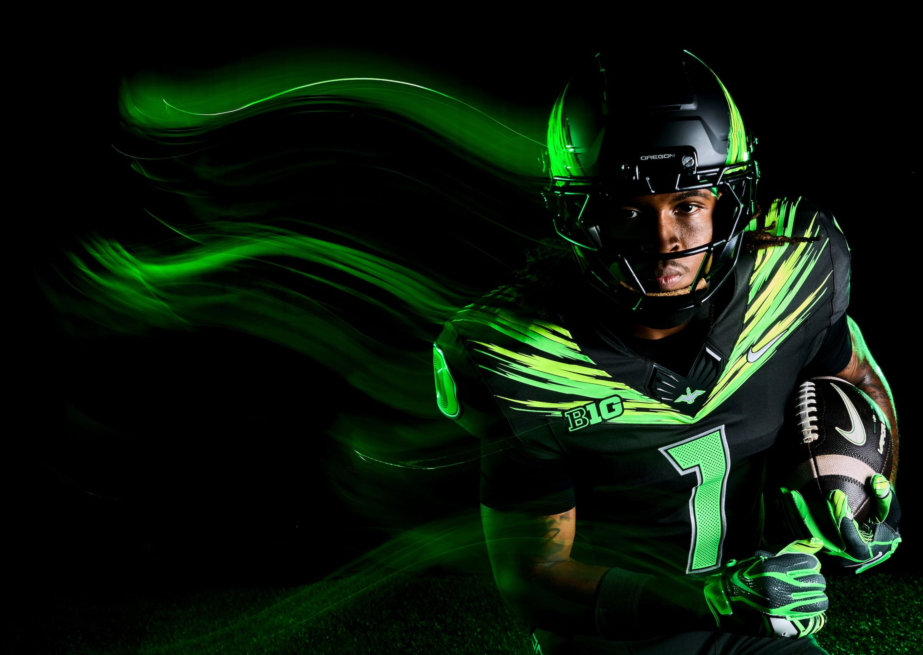 A football player wearing an Oregon Ducks uniform, holding a football.