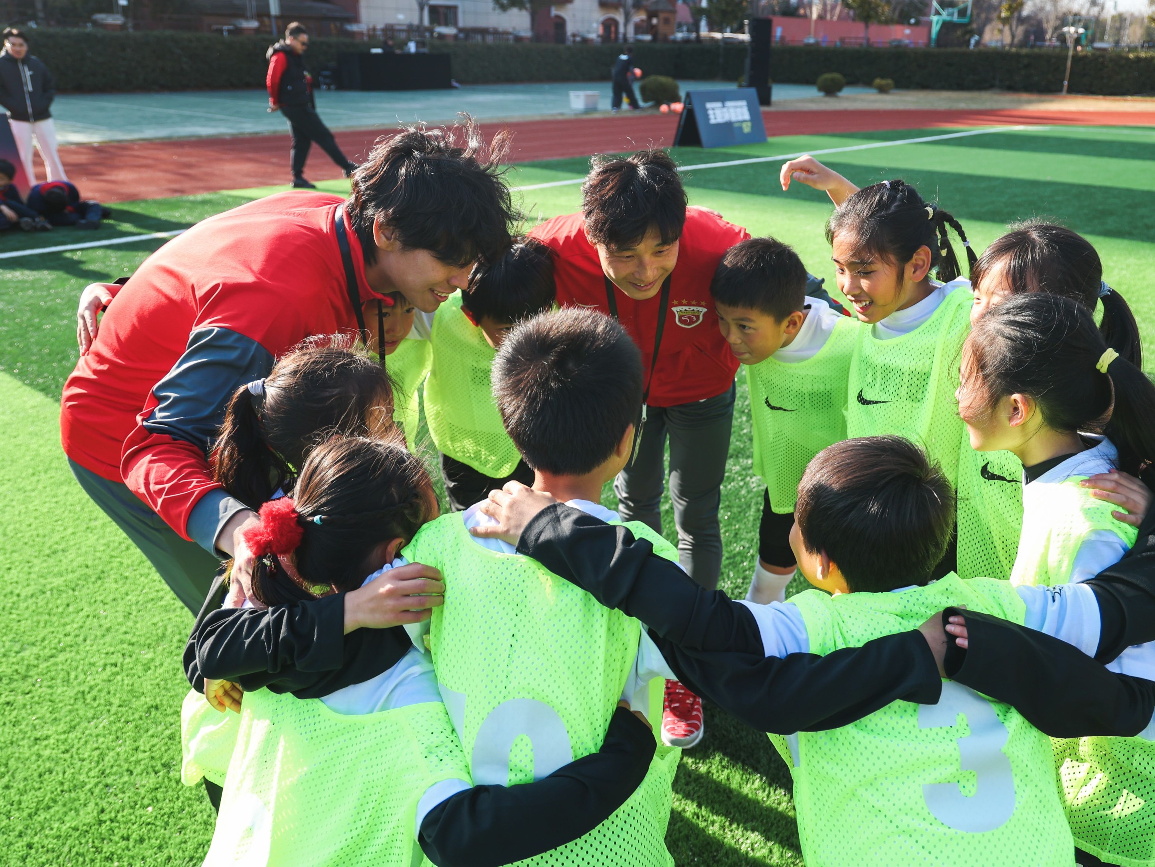A group of kids huddles with Nike coaches in Haigang, China.