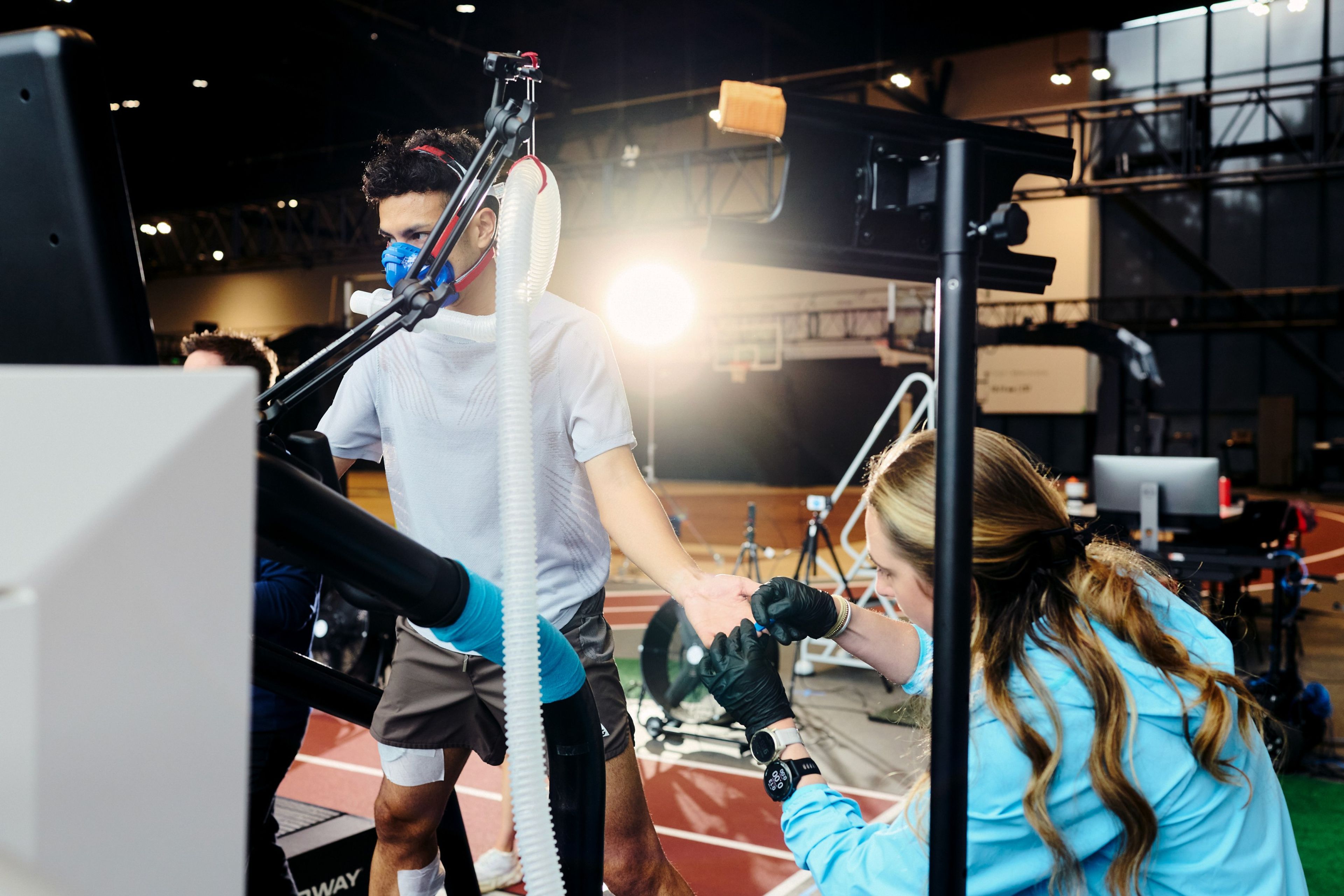 A male runner on a treadmill wearing a respiratory mask for performance testing in the Nike Sport Research Lab.