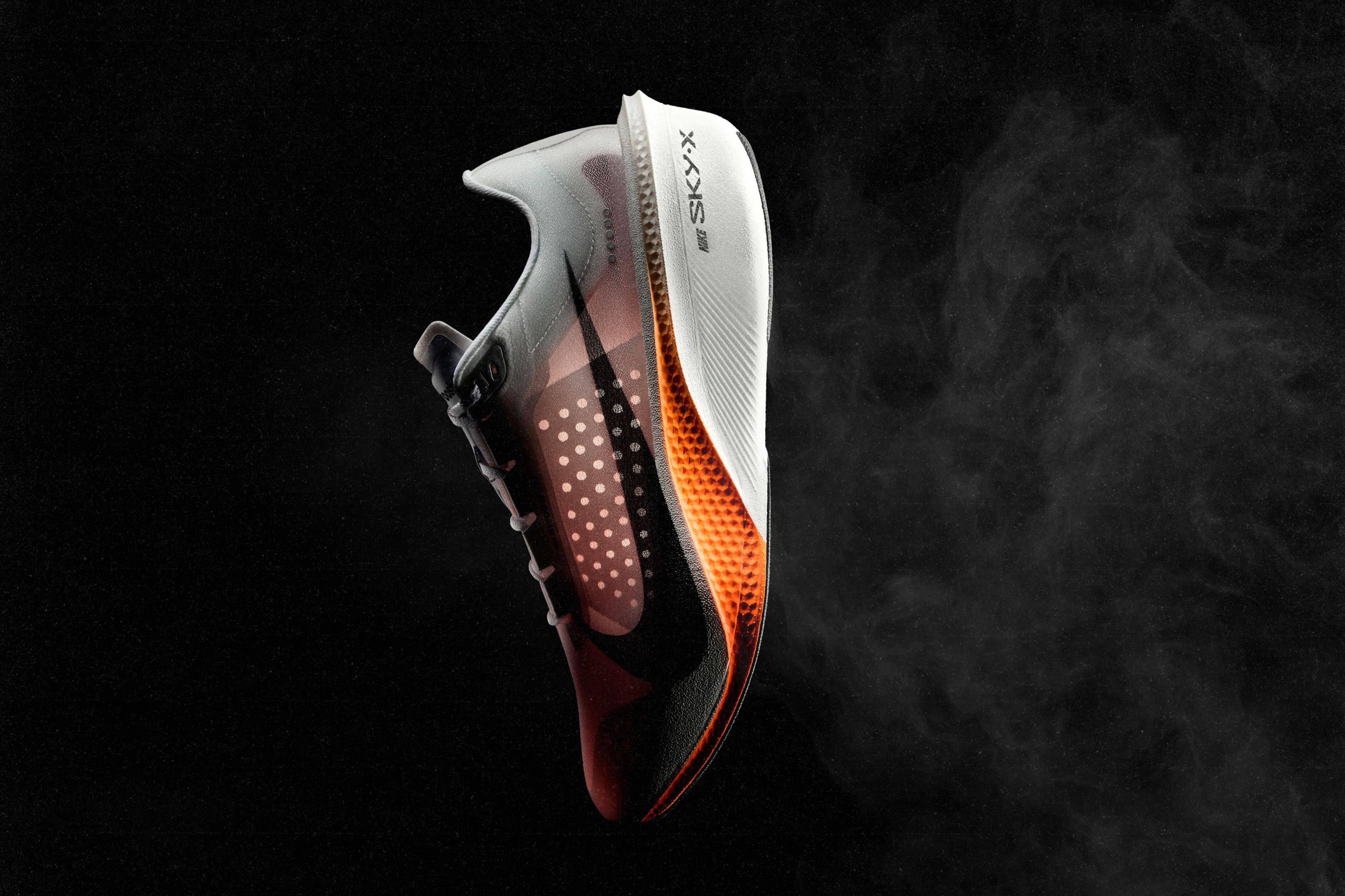 The Nike Swooshfly running shoe in white, black and orange floats against a dark background, showcasing its translucent upper and textured midsole.