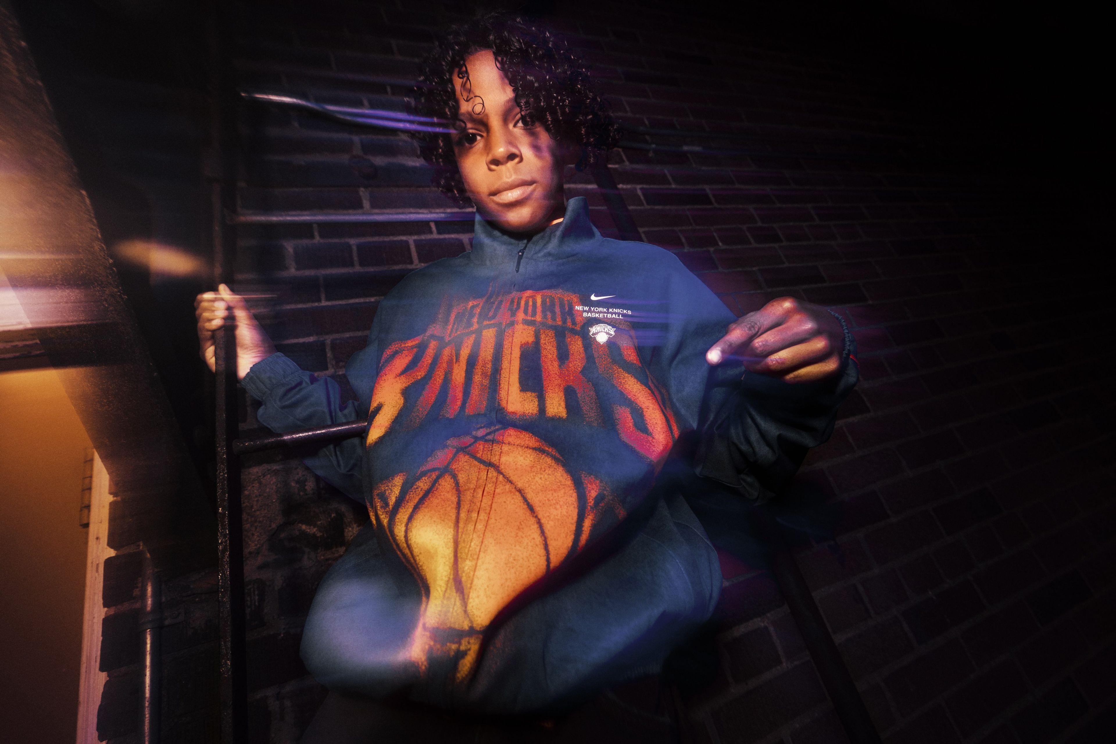 A child is pictured in a blue and orange New York Knicks hoodie from Nike's NBA Standard Issue Collection.