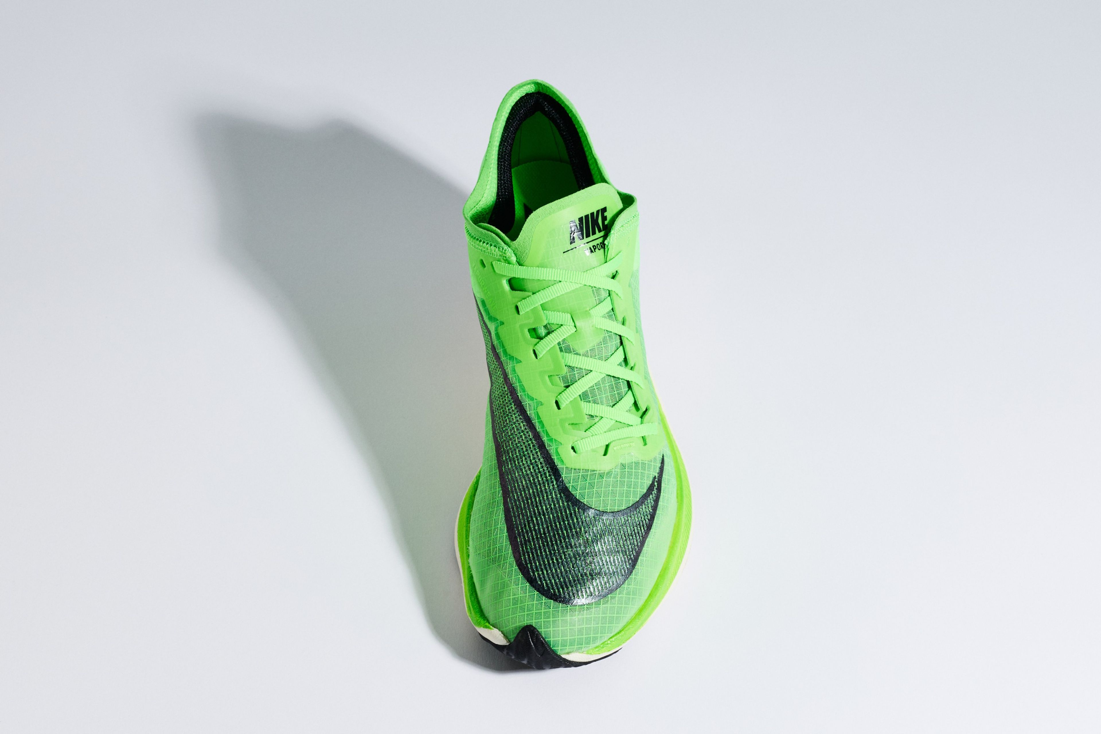 A bright green Nike ZoomX Vaporfly Next% running shoe with a black Swoosh logo, shown from a top-down angle against a light grey background.