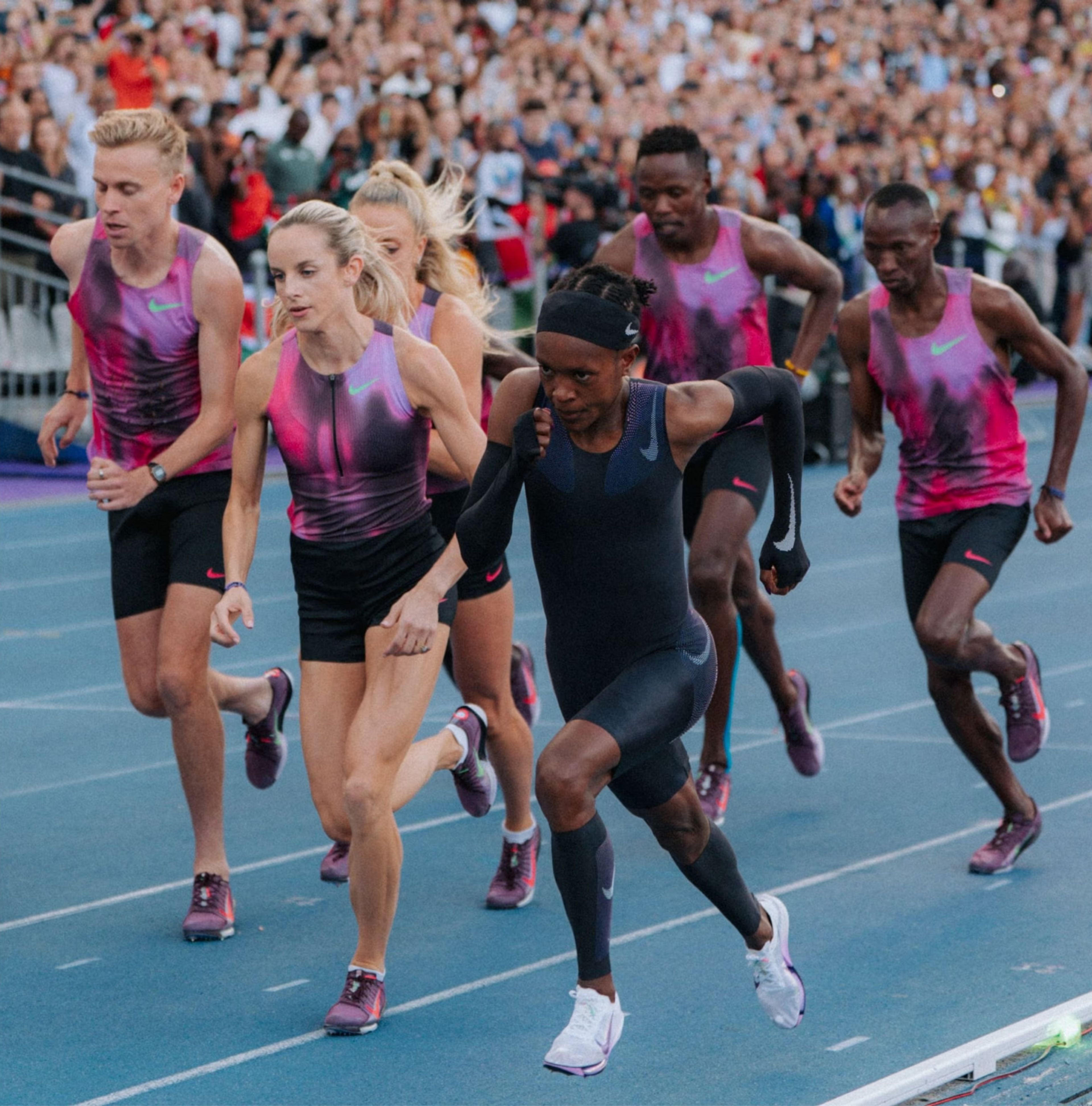 Middle-distance champion Faith Kipyegon runs on a track alongside five pacers while wearing a Nike speed kit.
