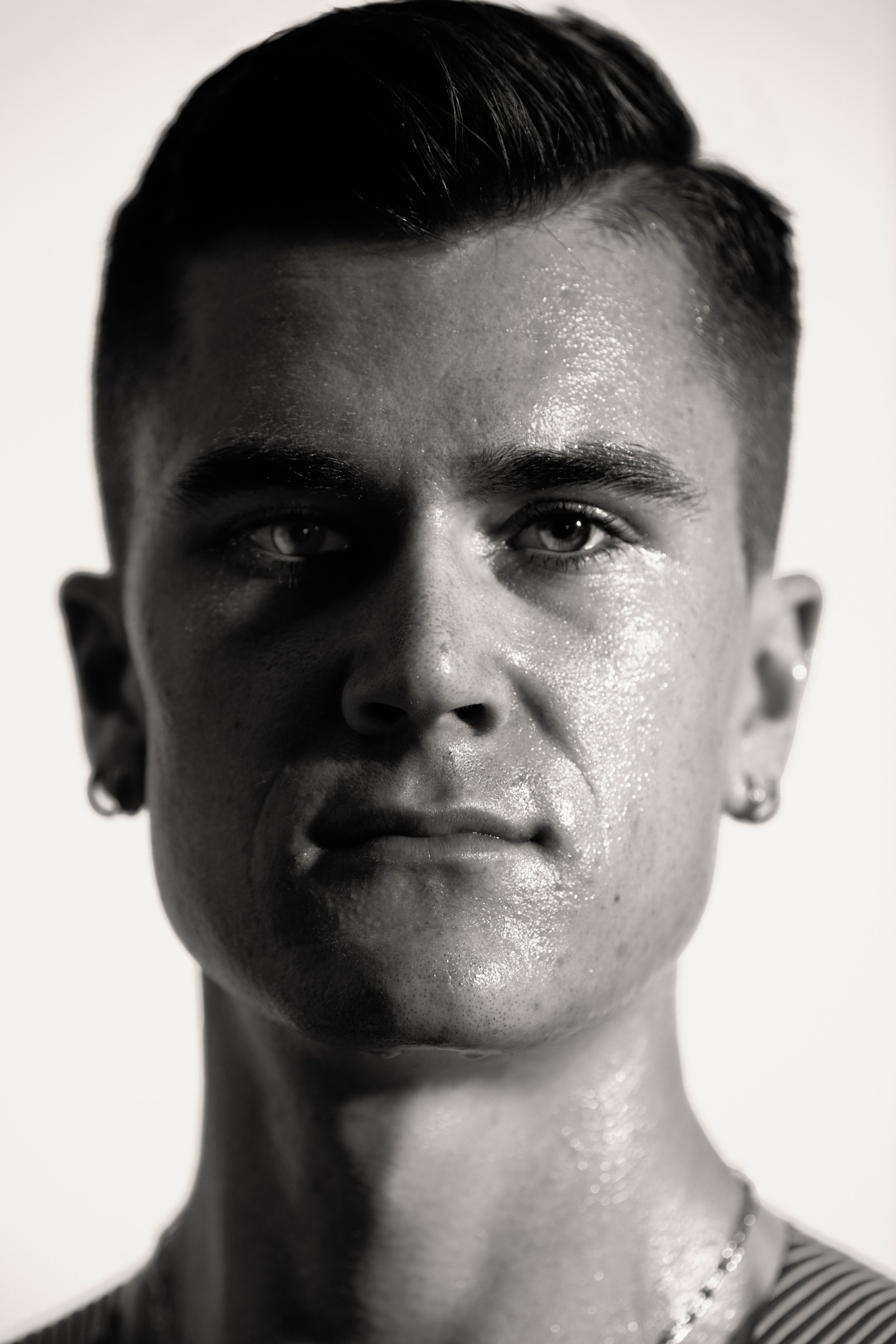 Black and white close up photo of Jacob Ingebrigtsen's face. His face is partly covered in shadow, as he looks unsmiling directly at the camera.
