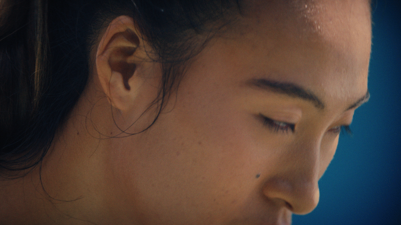 Video loop of Qinwen Zheng raising her eyes, potentially before a serve. Her face is framed on a blue background.